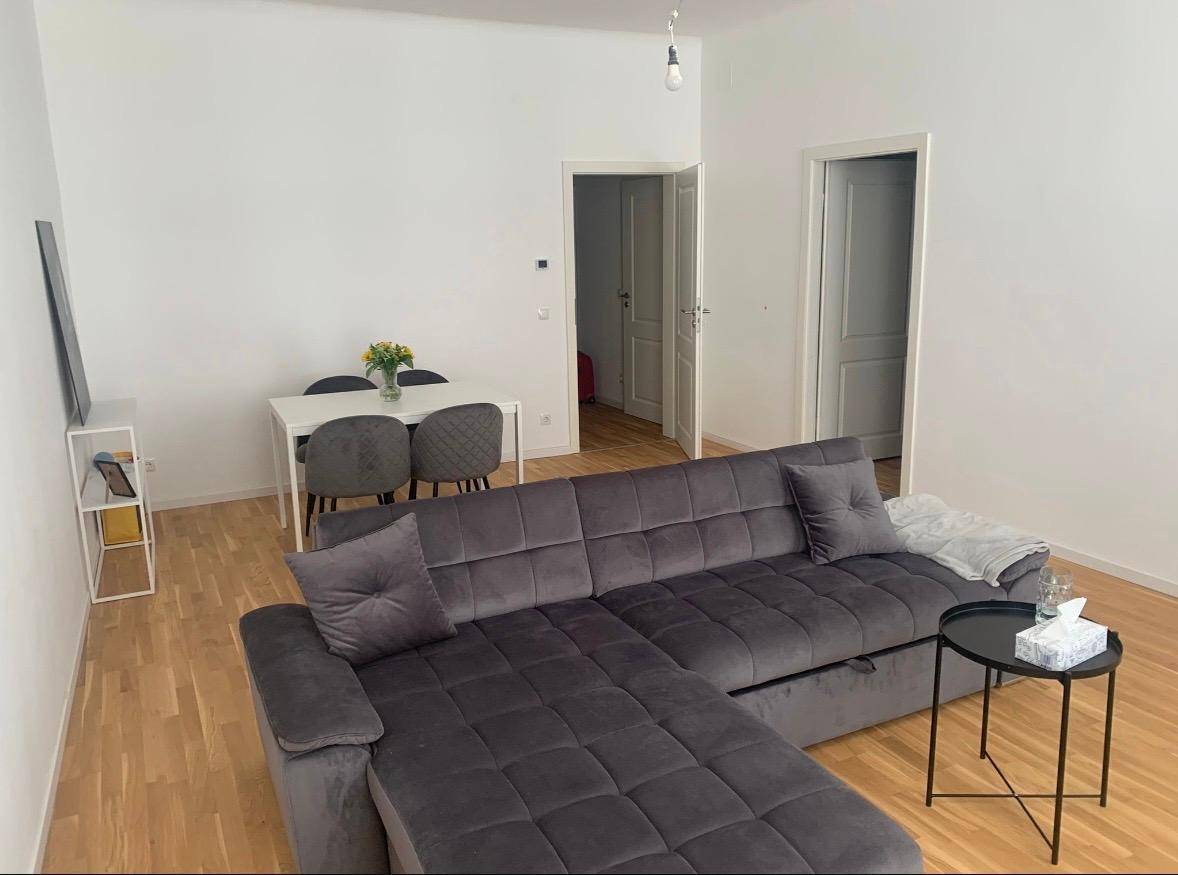 Gemütlicher Wohn-Essbereich mit großem Ecksofa, Esstisch und hellem Holzboden.