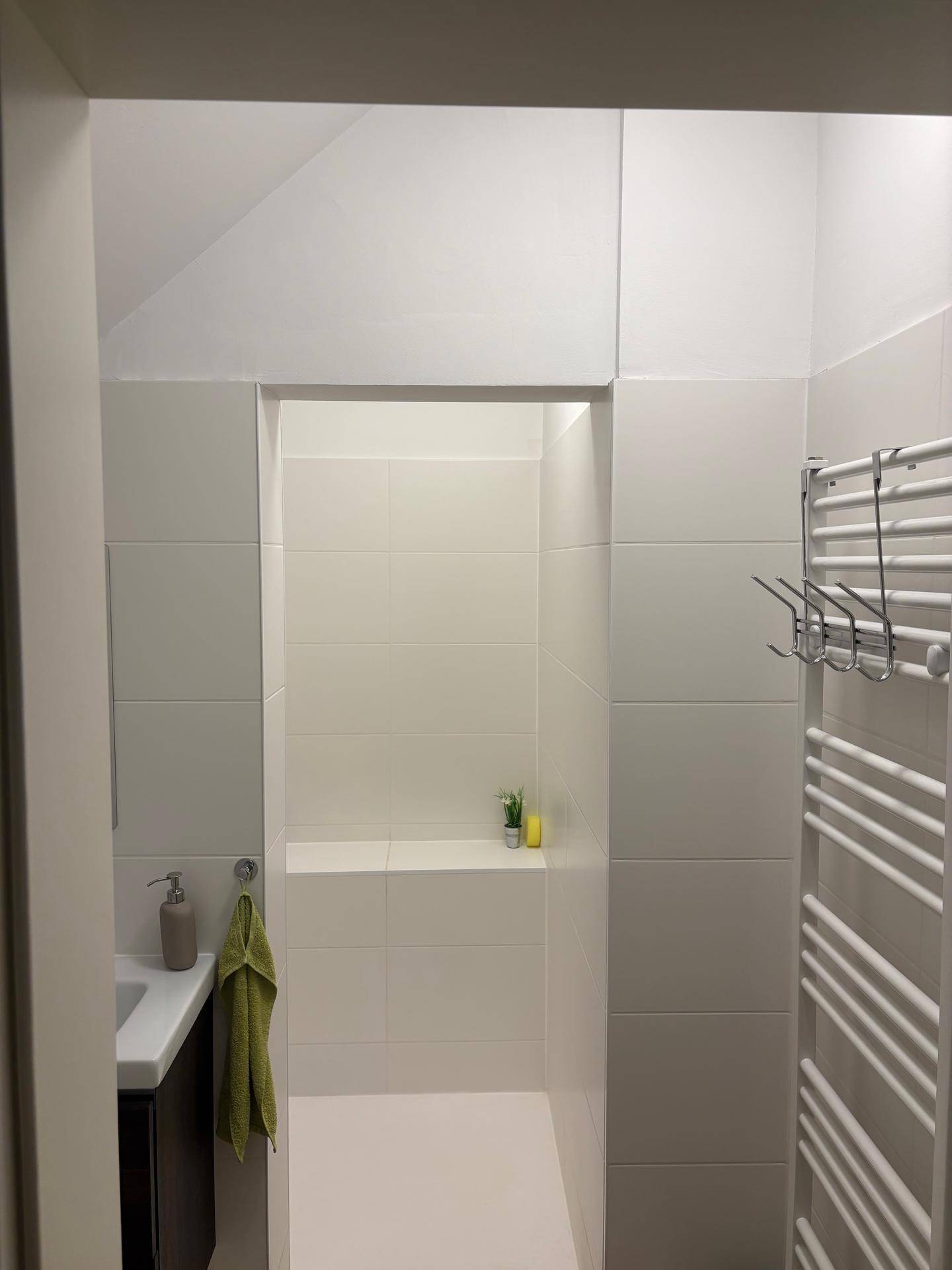 Modernes Badezimmer mit begehbarer Dusche und weiß gefliesten Wänden, inklusive Handtuchheizkörper.