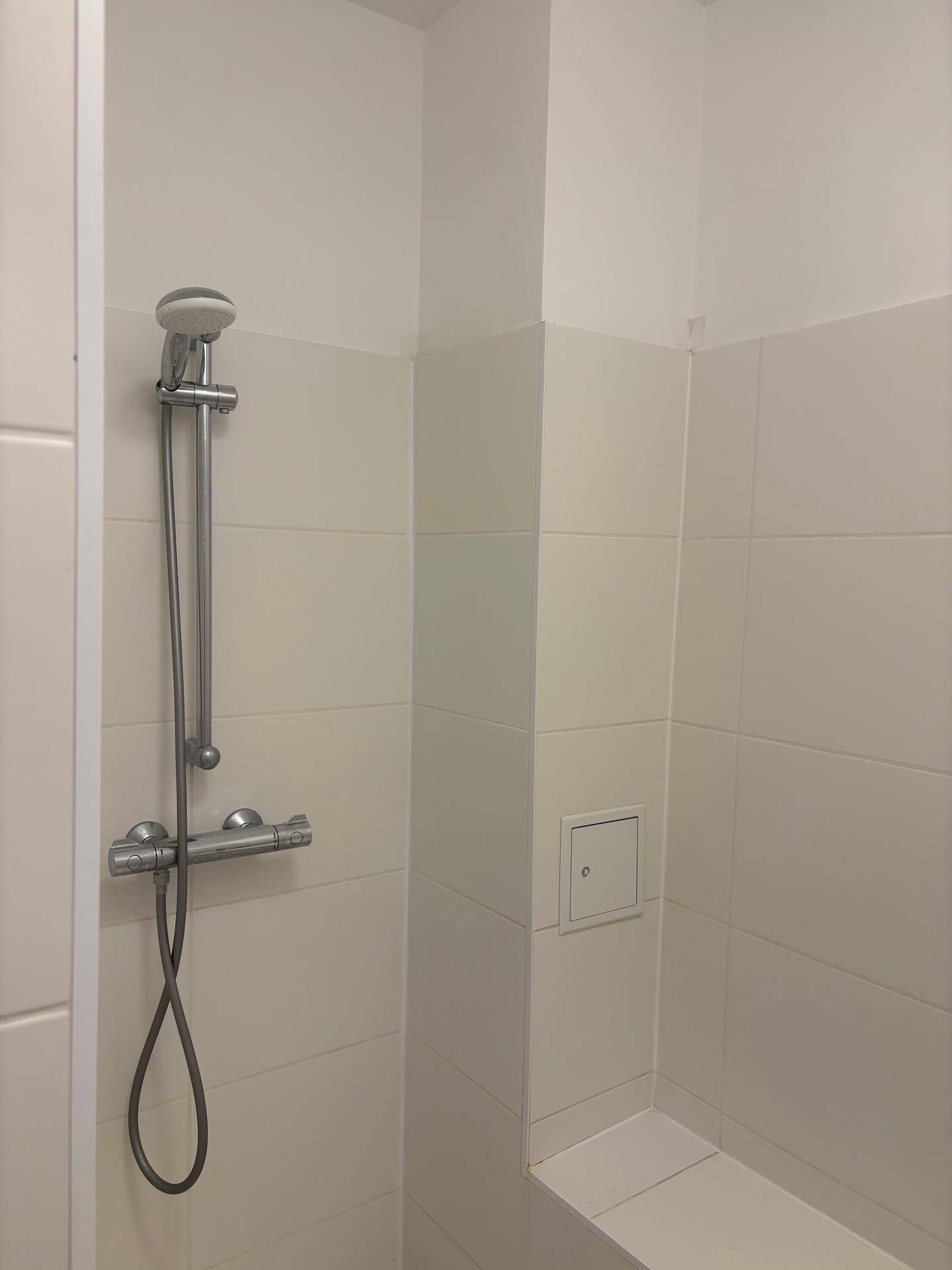 Detaillierte Ansicht der Duscharmatur und der weißen Fliesen in einem modernen Badezimmer.