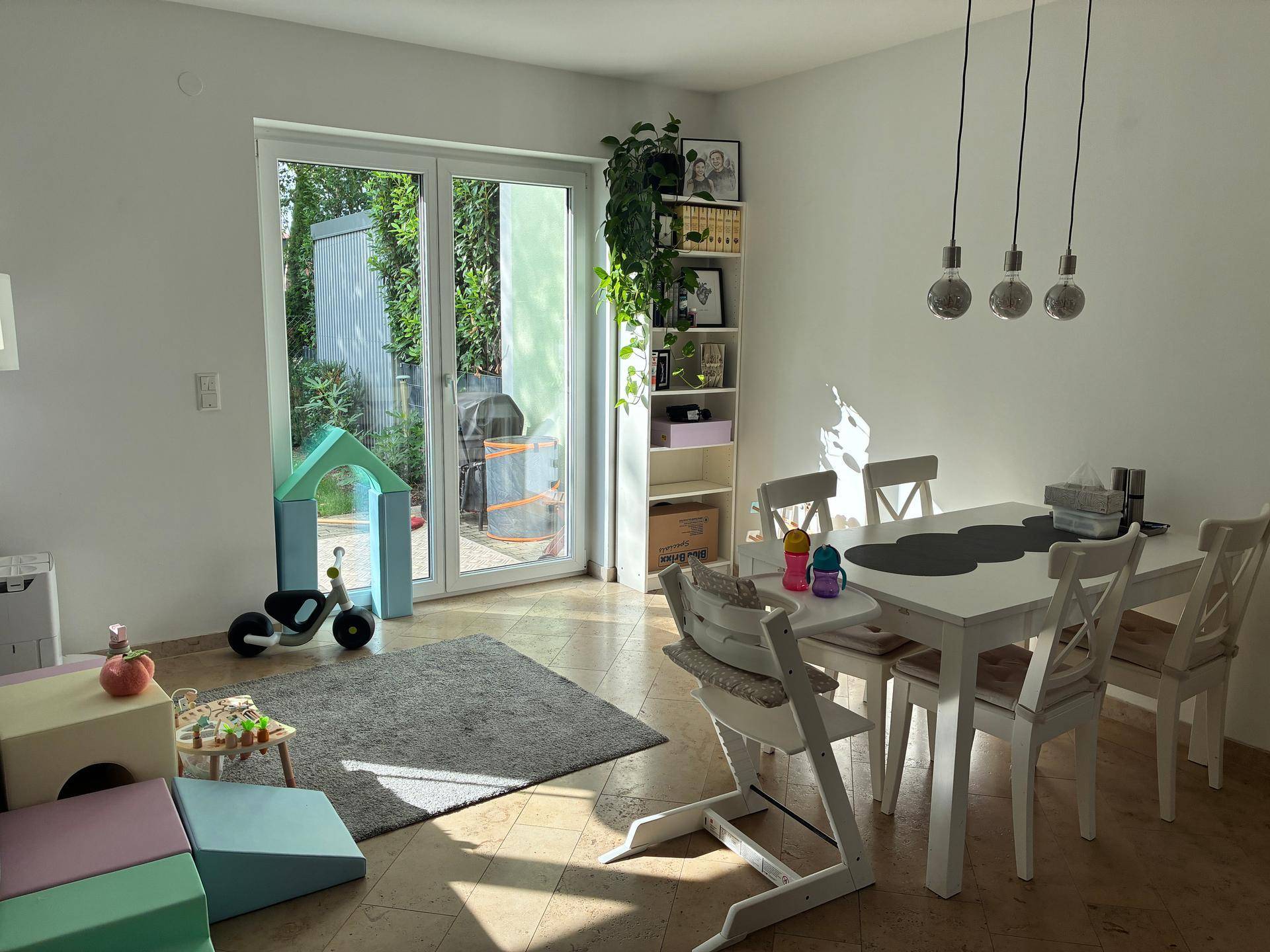 Heller Essbereich mit Zugang zum Garten, Fliesenboden und Kinderspielzeug.