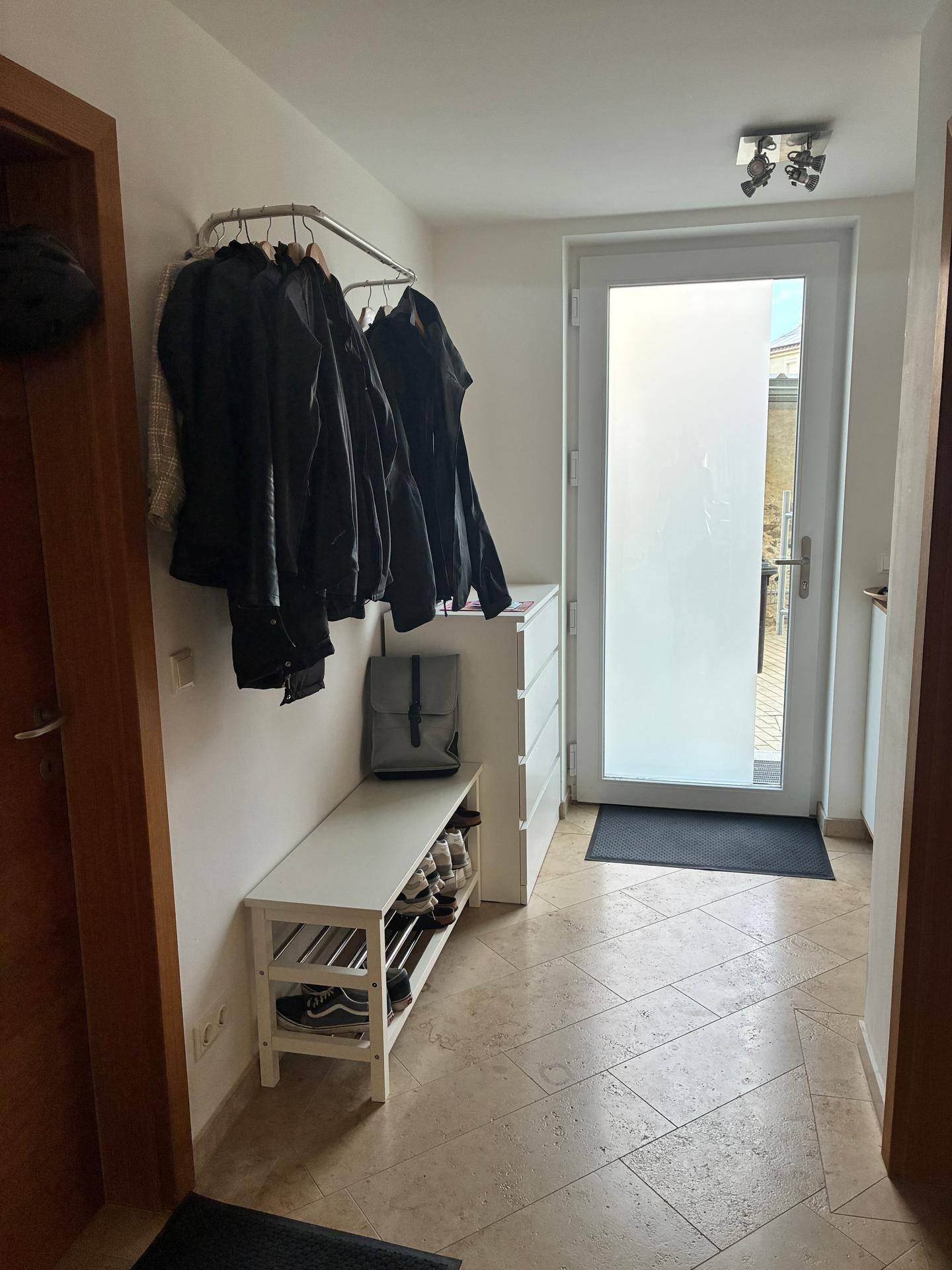 Eingangsbereich mit heller Fliese, Garderobe und einer modernen Haustür mit Milchglas.