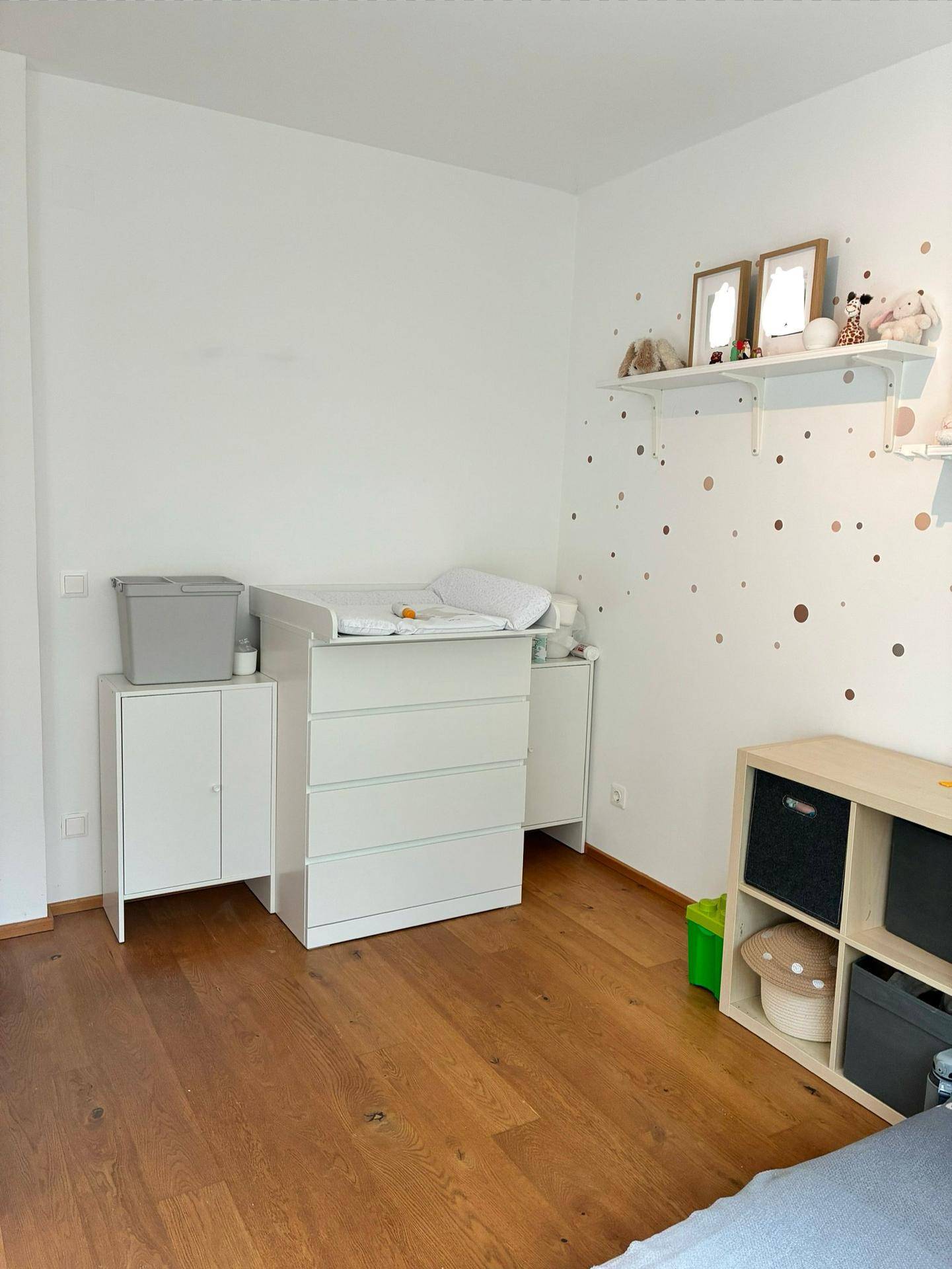 Kinderzimmer mit Wickelkommode, Holzboden und verspielter Wanddekoration.
