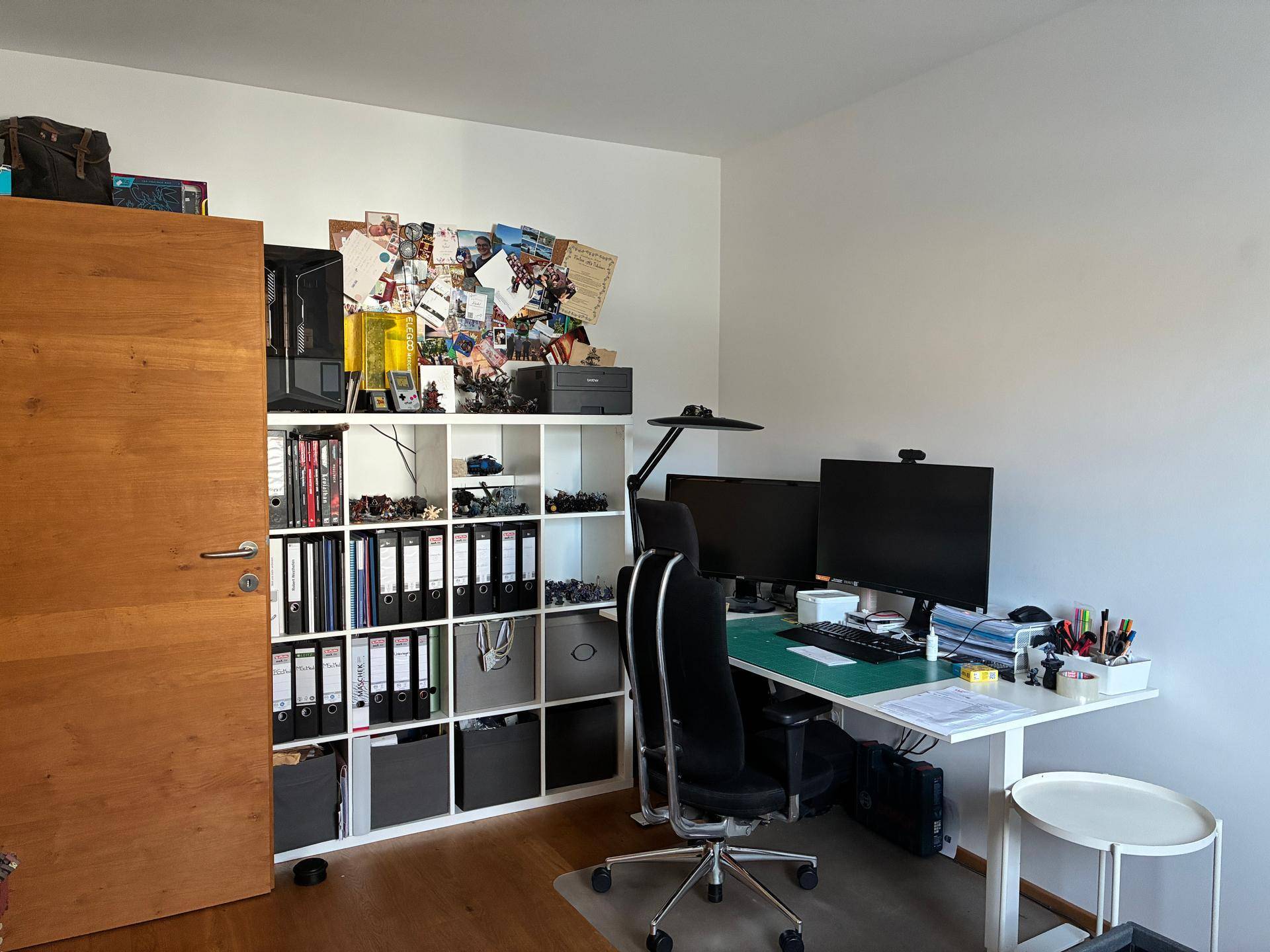 Arbeitszimmer mit Holzboden, Schreibtisch und Regalen voller Ordner und Dekoration.