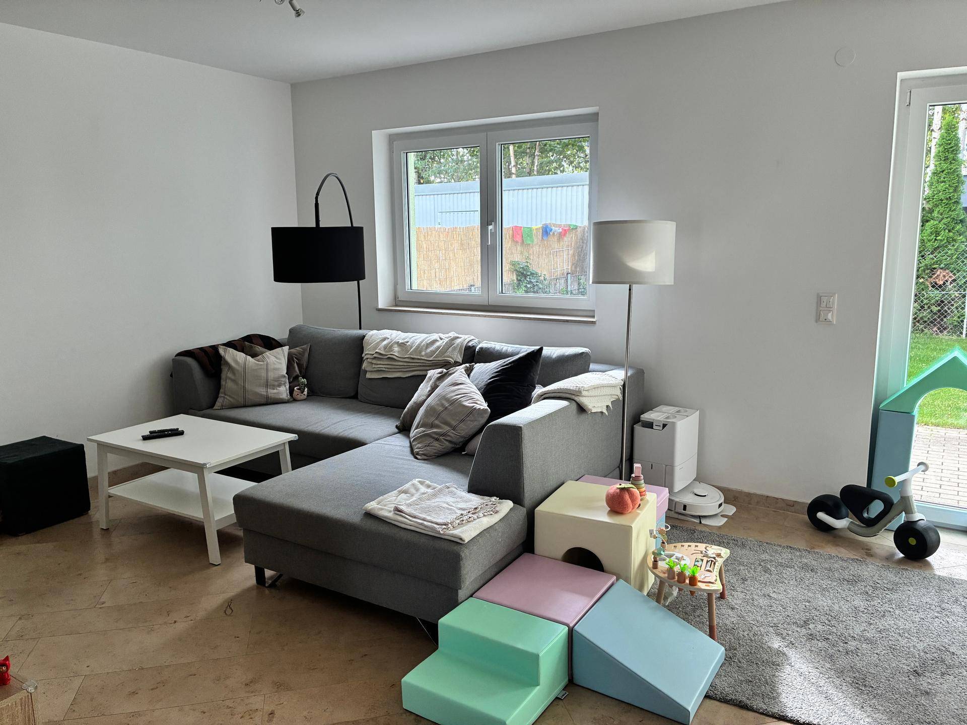 Helles Wohnzimmer mit großem Ecksofa, Fenstern und Zugang zum Garten.