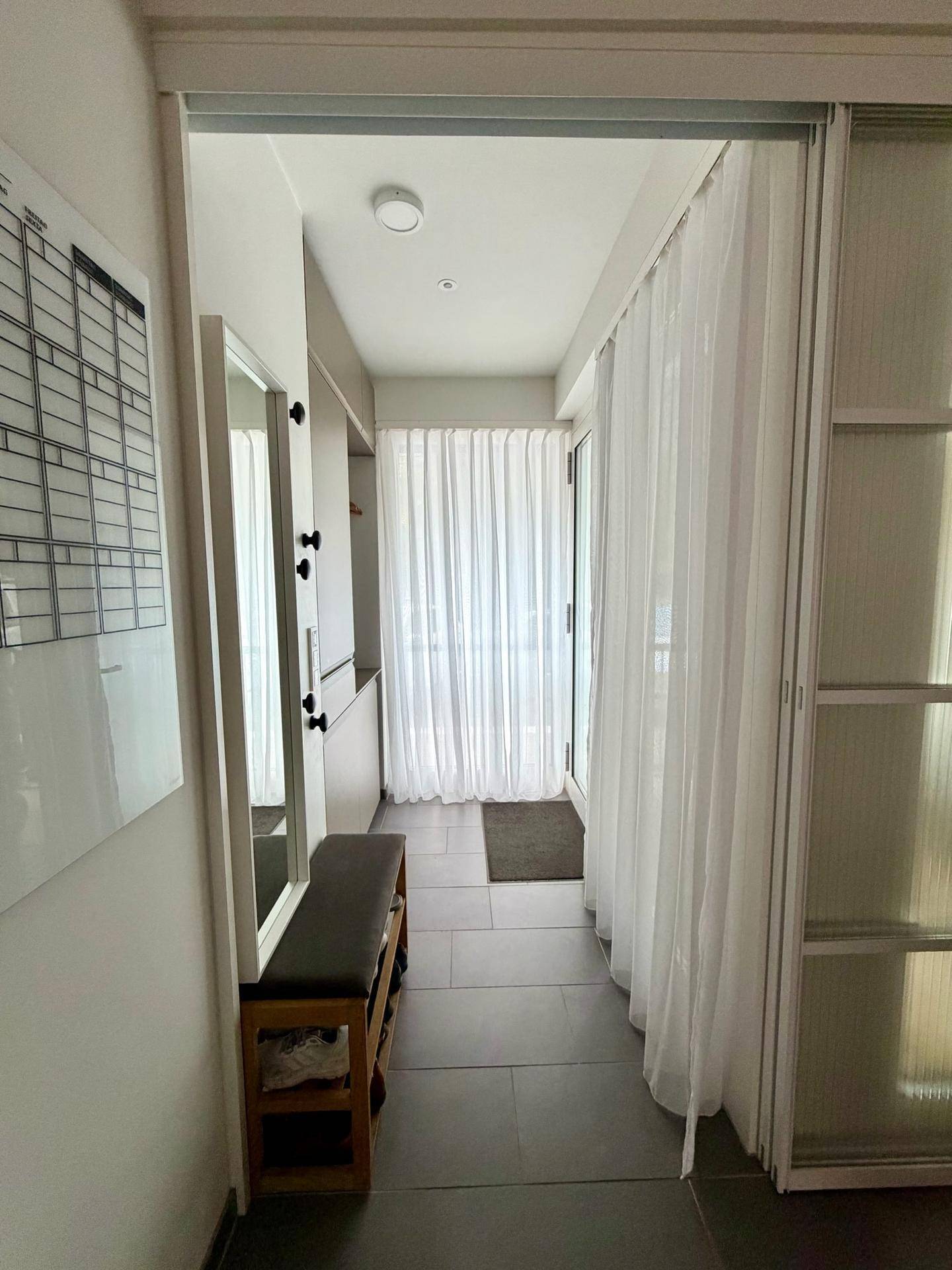 Langer, heller Flur mit Vorhängen, der zu einem Außenbereich führt.