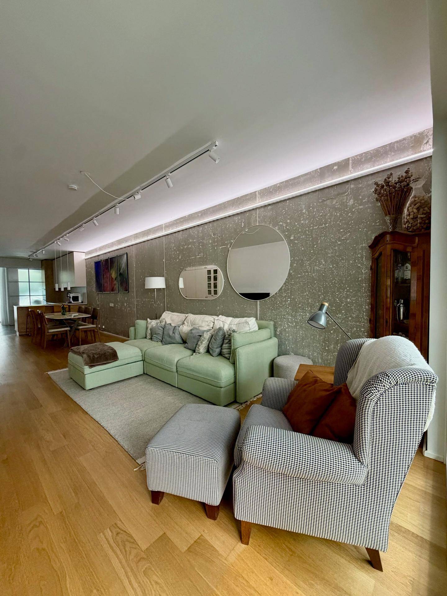 Komfortables Wohnzimmer mit grünem Sofa und Sessel, offen zum Essbereich.