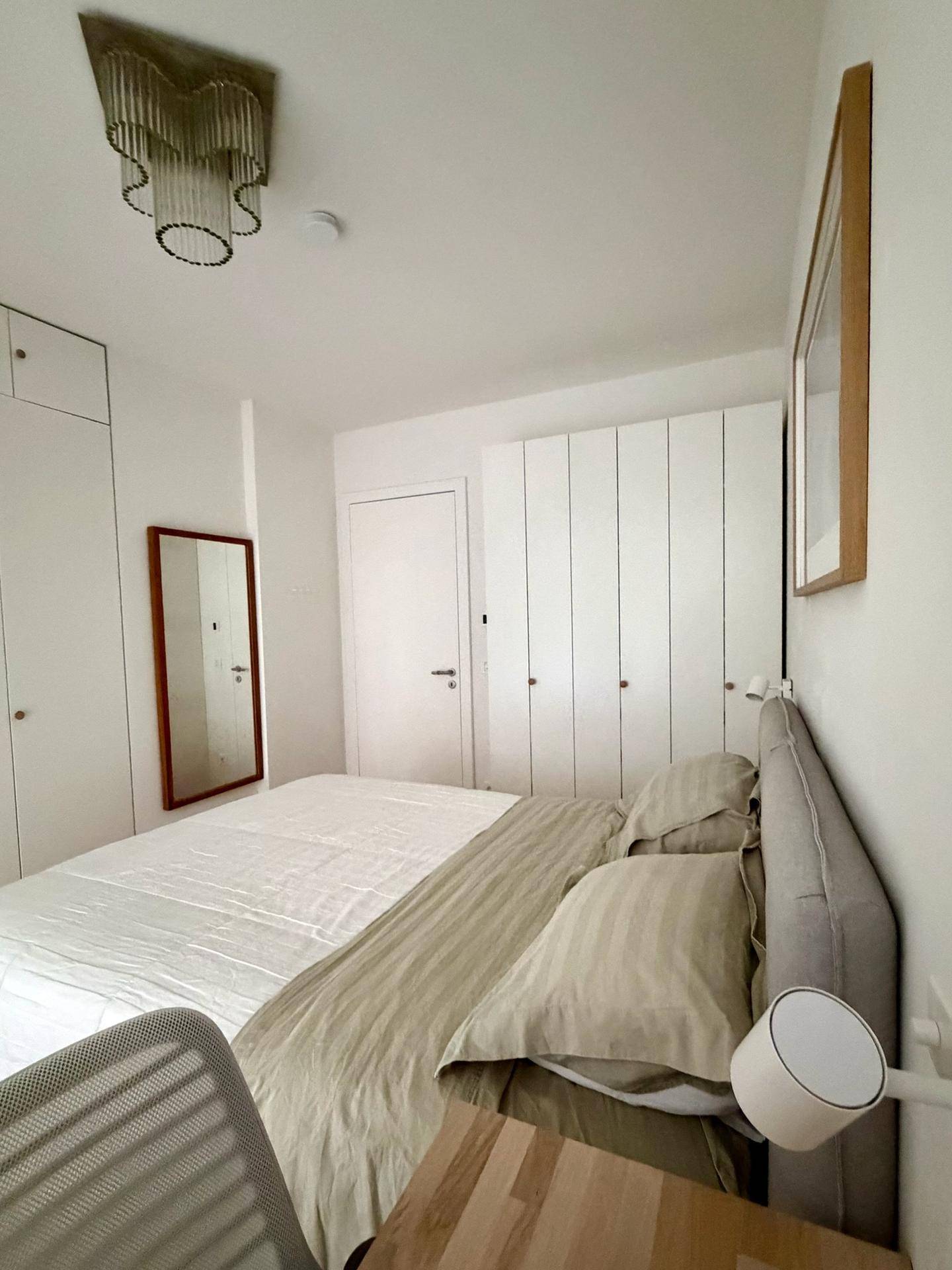 Schlafzimmer mit Bett, Spiegel und integrierten weißen Kleiderschränken.