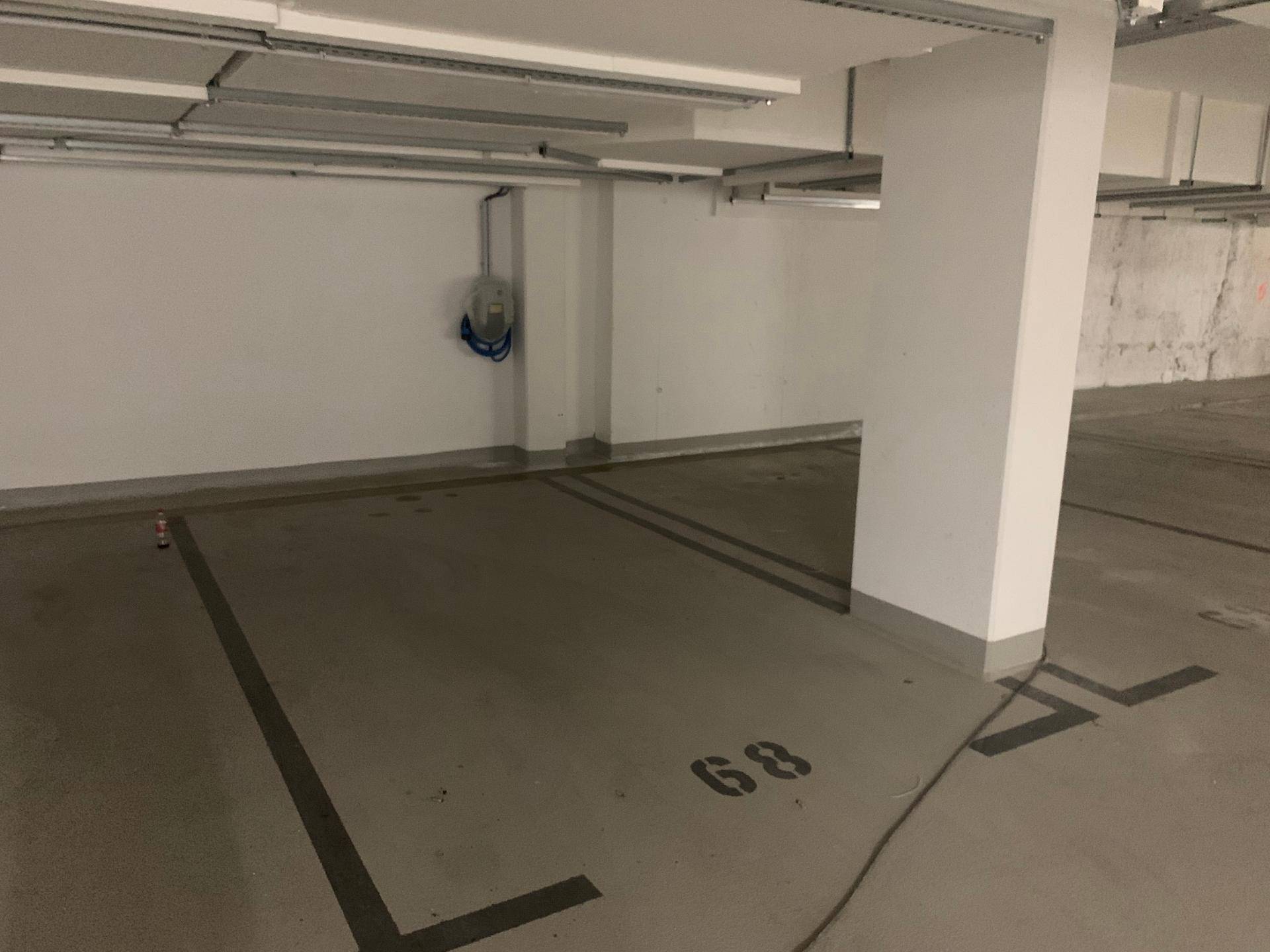 Tiefgarage mit markiertem Stellplatz und Ladestation für Elektrofahrzeuge.
