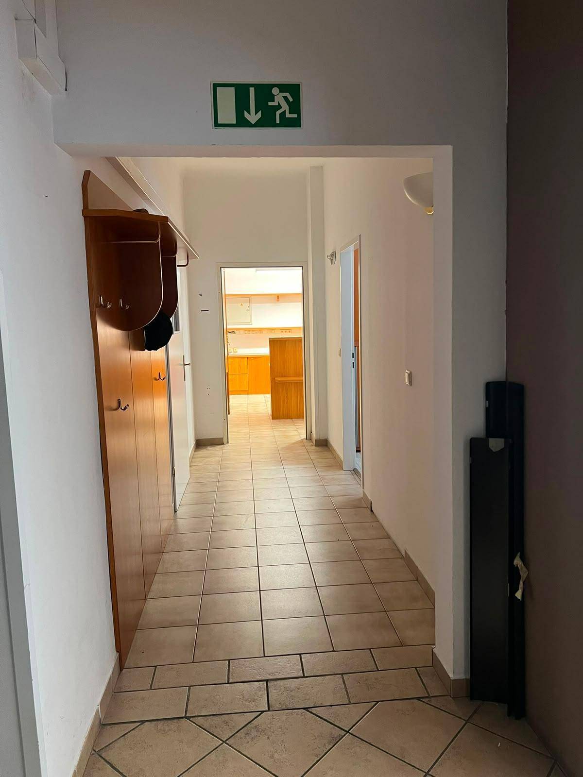Langer Flur mit Fliesenboden und Garderobe, der zu weiteren Räumen führt.