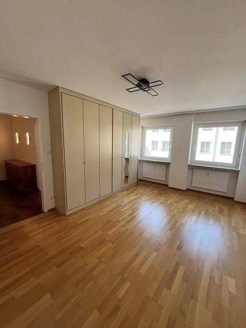 Helles Schlafzimmer mit Parkettboden, großem Einbauschrank und zwei Fenstern für viel Tageslicht.