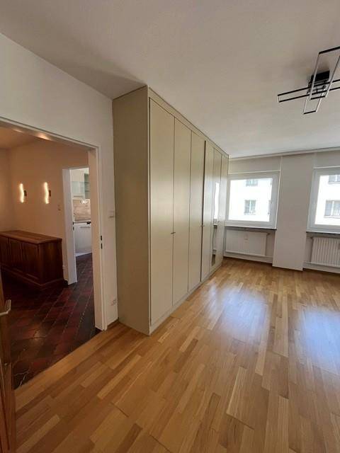Geräumiges Schlafzimmer mit hellem Parkettboden, Einbauschrank und Zugang zum Flur.