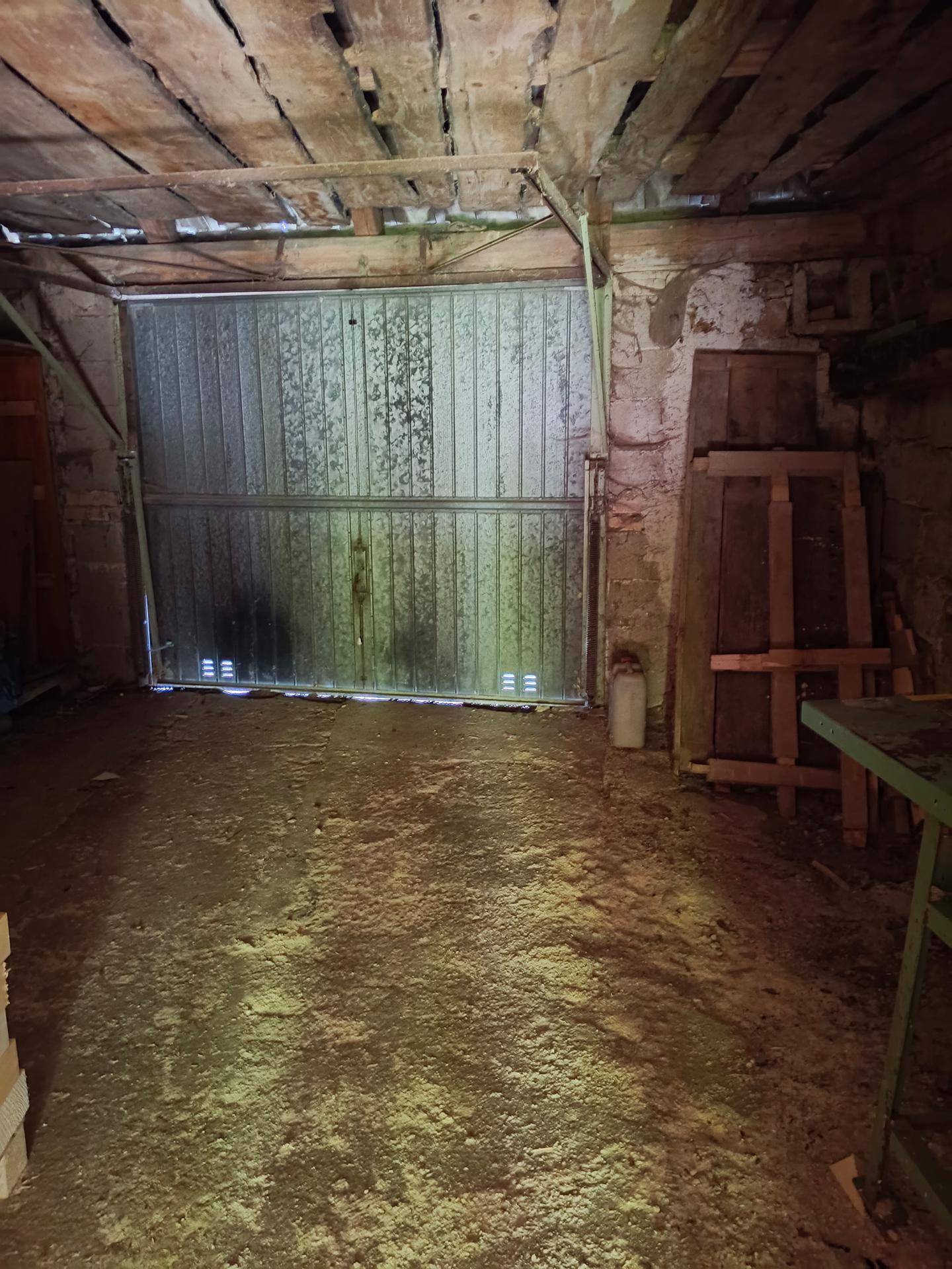Rustikale Garage oder Scheune mit Holzbalkendecke und Metalltor.