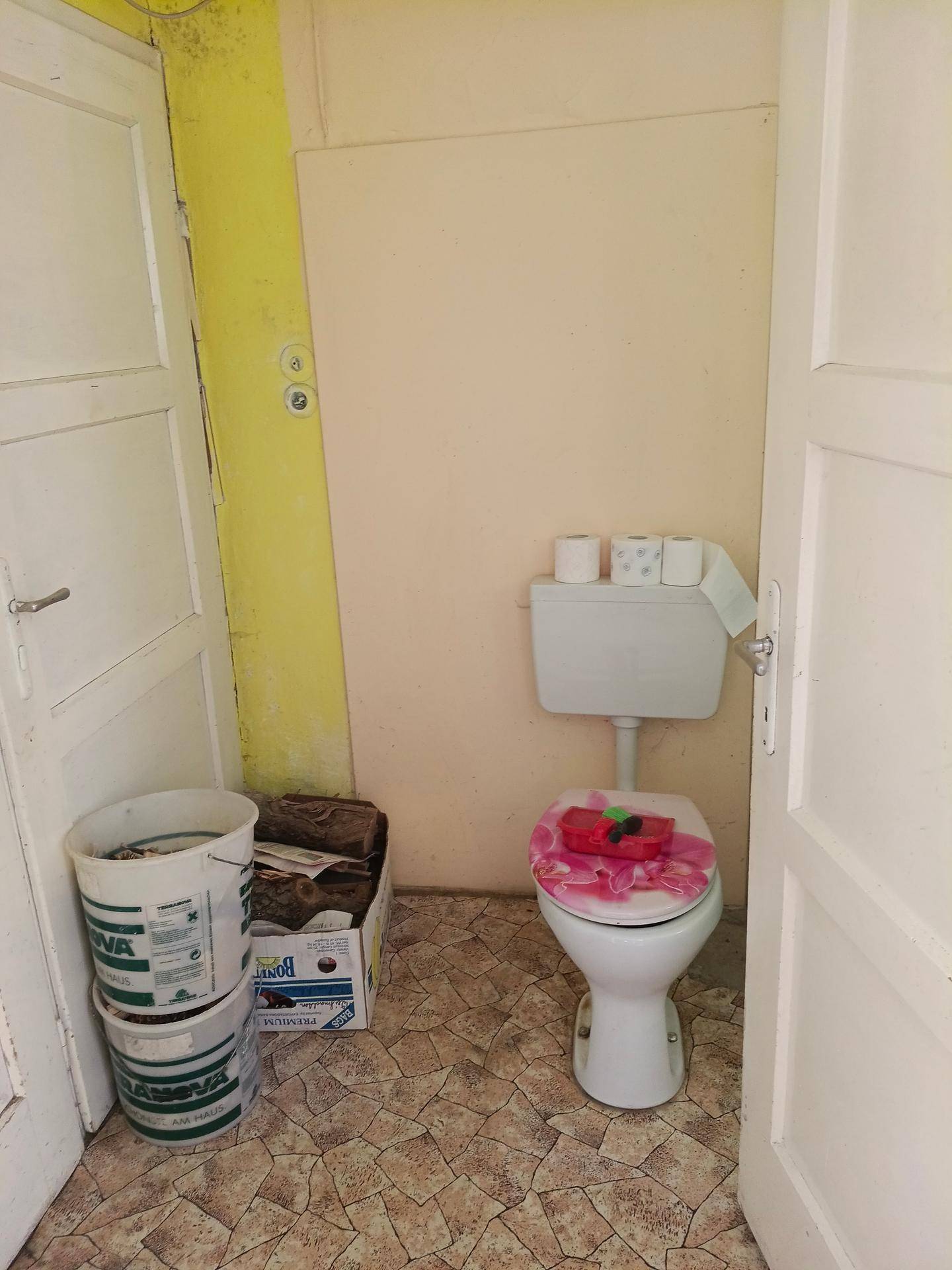 Separate Toilette mit einfacher Ausstattung und Fliesenboden.