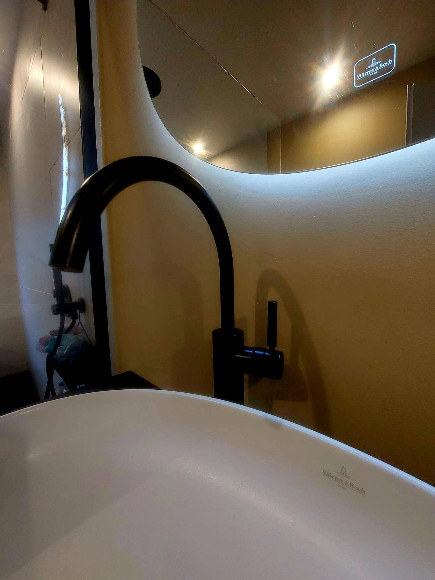 Detailaufnahme eines modernen schwarzen Wasserhahns über einem Waschbecken in einem Badezimmer.