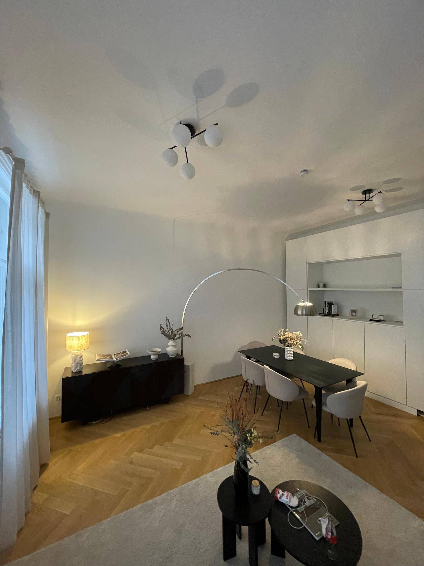 Moderner Wohn-Essbereich mit Esstisch, Bogenlampe und integrierten Schränken.