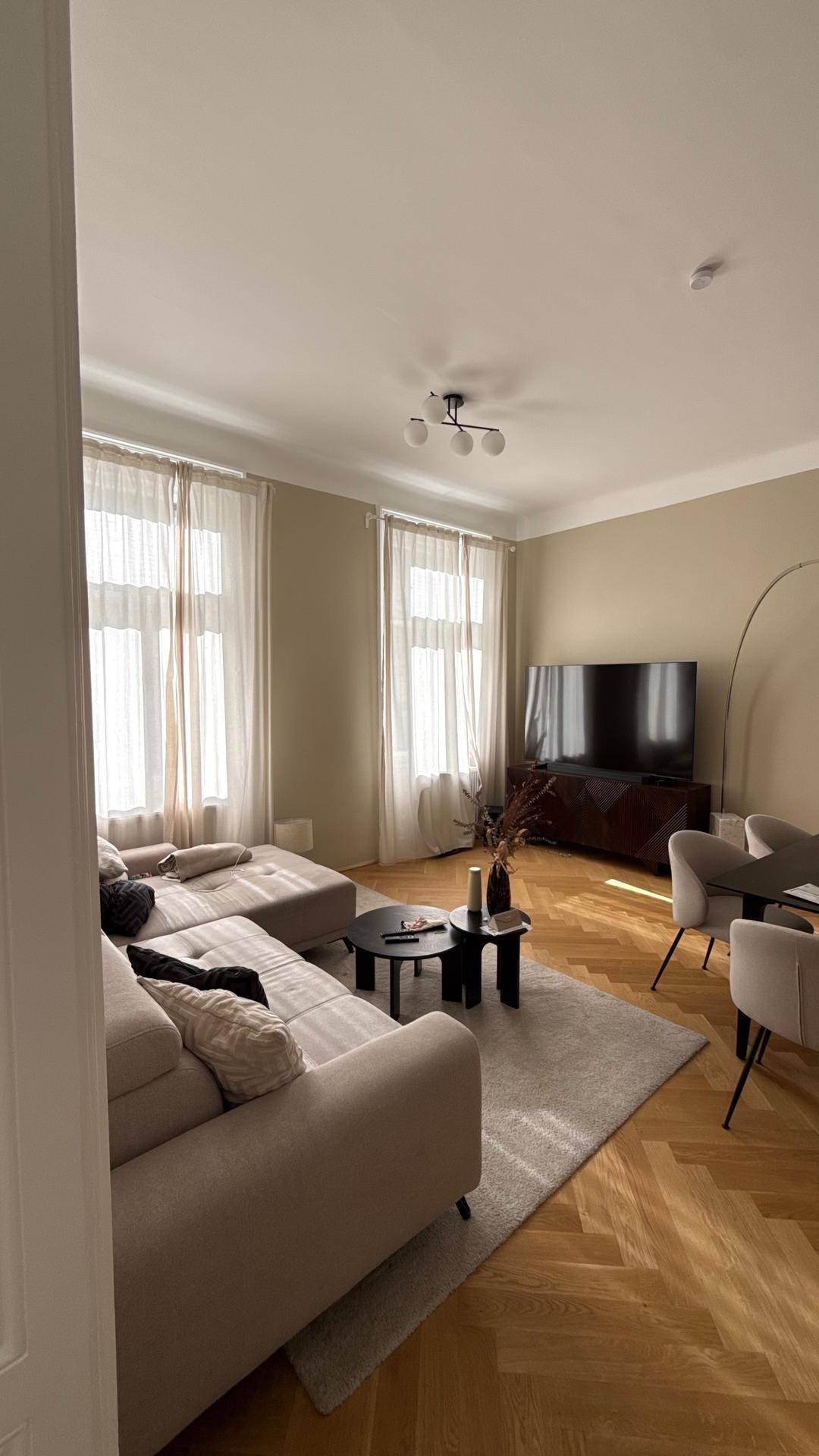 Geräumiger Wohn-Essbereich mit Sofa, Fernseher und Esstisch im Hintergrund.