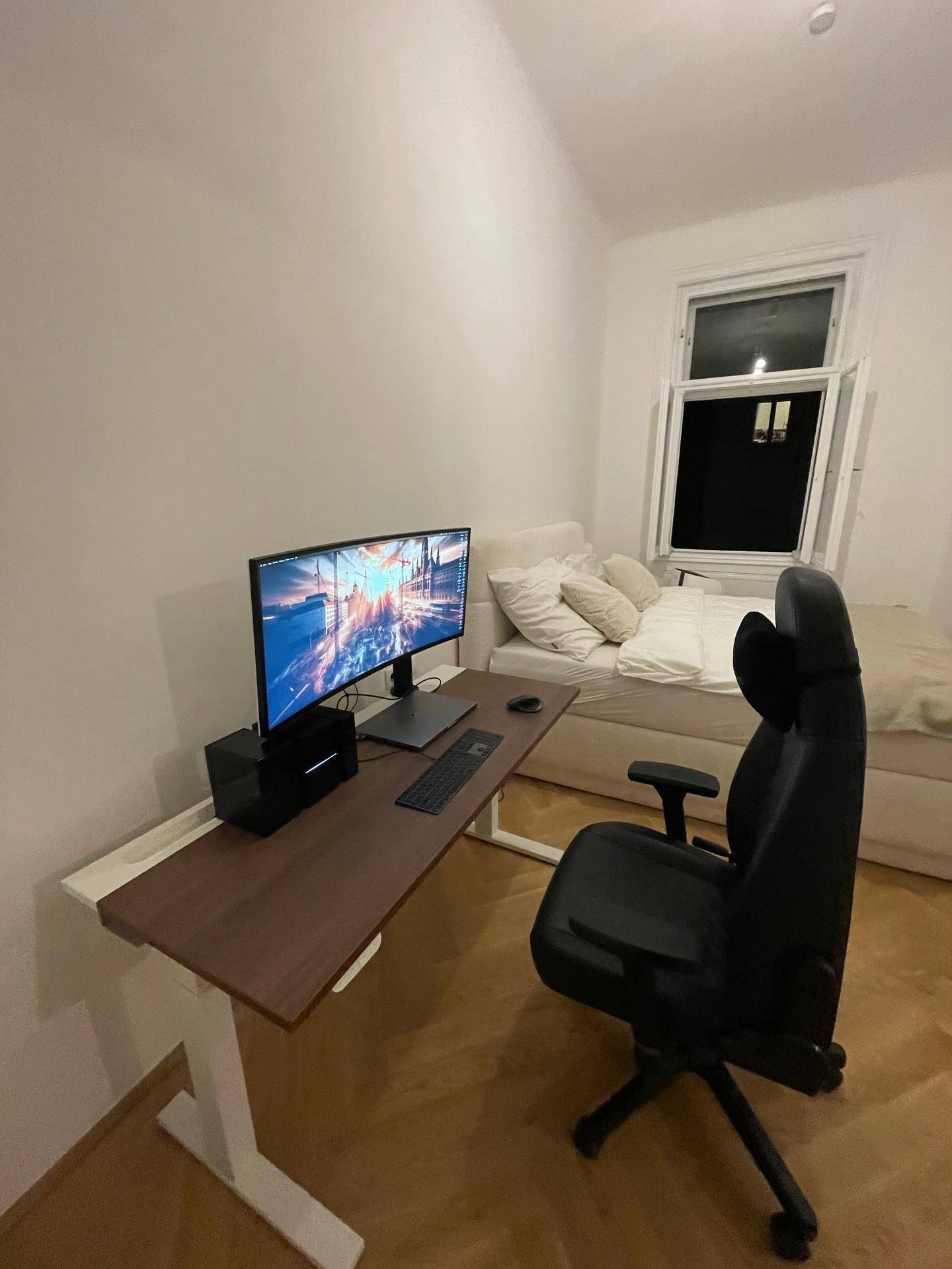 Schlafzimmer mit Arbeitsbereich, Schreibtisch, Monitor und Fenster.