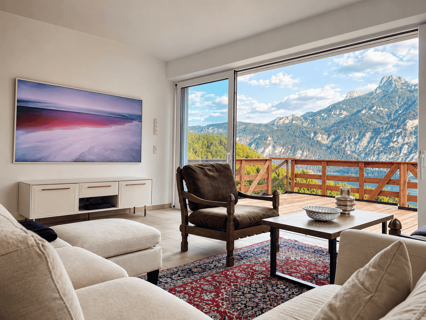 Gemütliches Wohnzimmer mit Sofa, Teppich und Zugang zu einer Terrasse mit Bergblick.