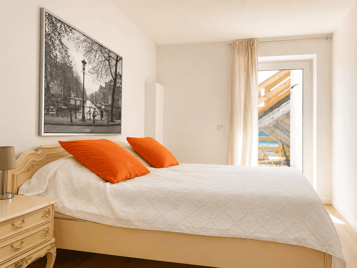Helles Schlafzimmer mit Doppelbett, Nachttisch und Zugang zu einem Balkon mit Seeblick.
