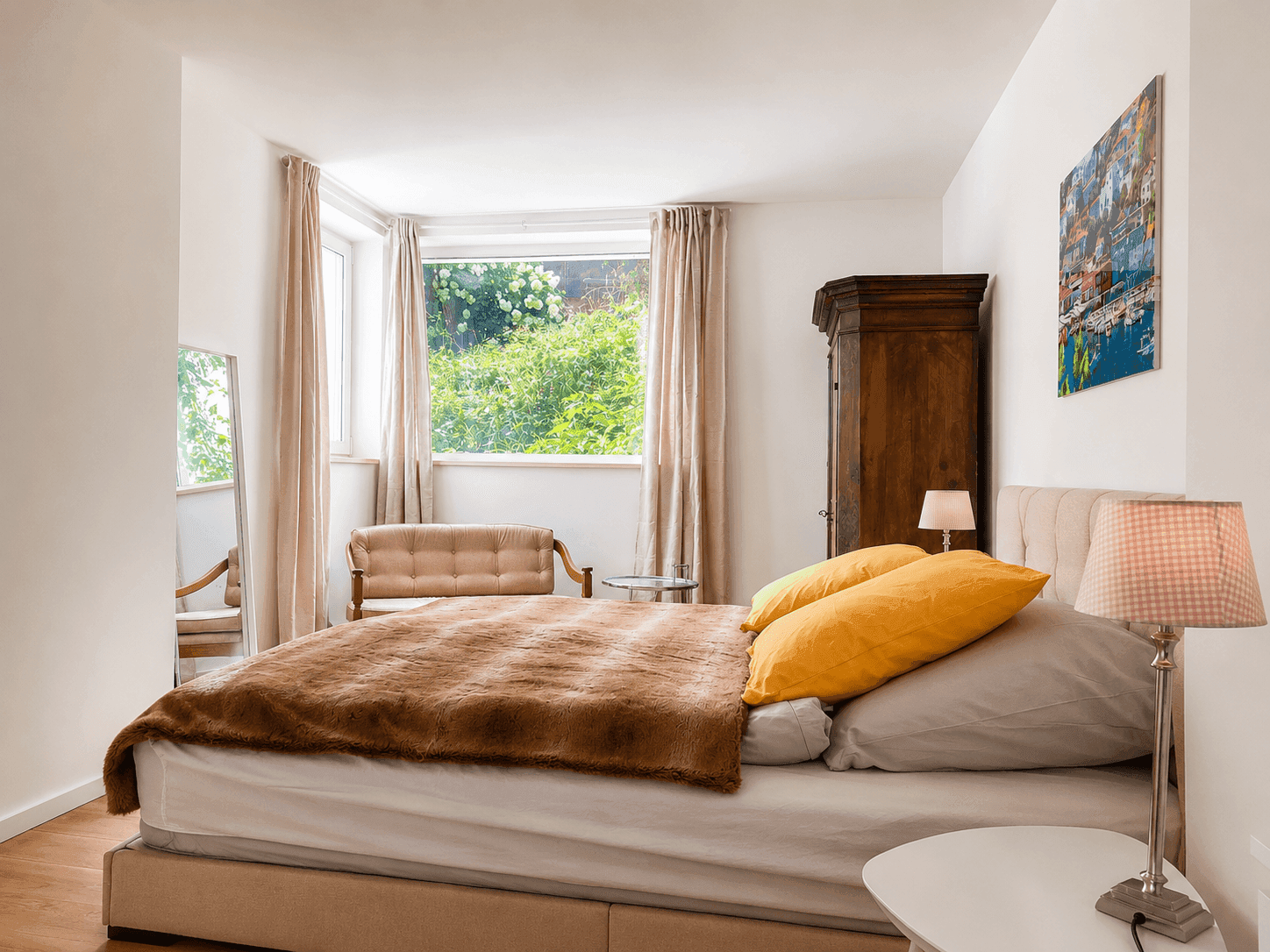 Schlafzimmer mit Doppelbett, großem Spiegel und Blick ins Grüne.