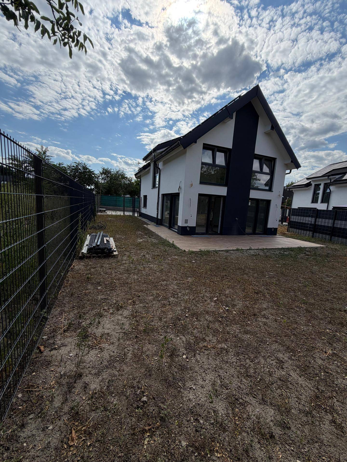 Weitläufiger Gartenbereich hinter dem Haus mit einer Terrasse und einem Zaun.