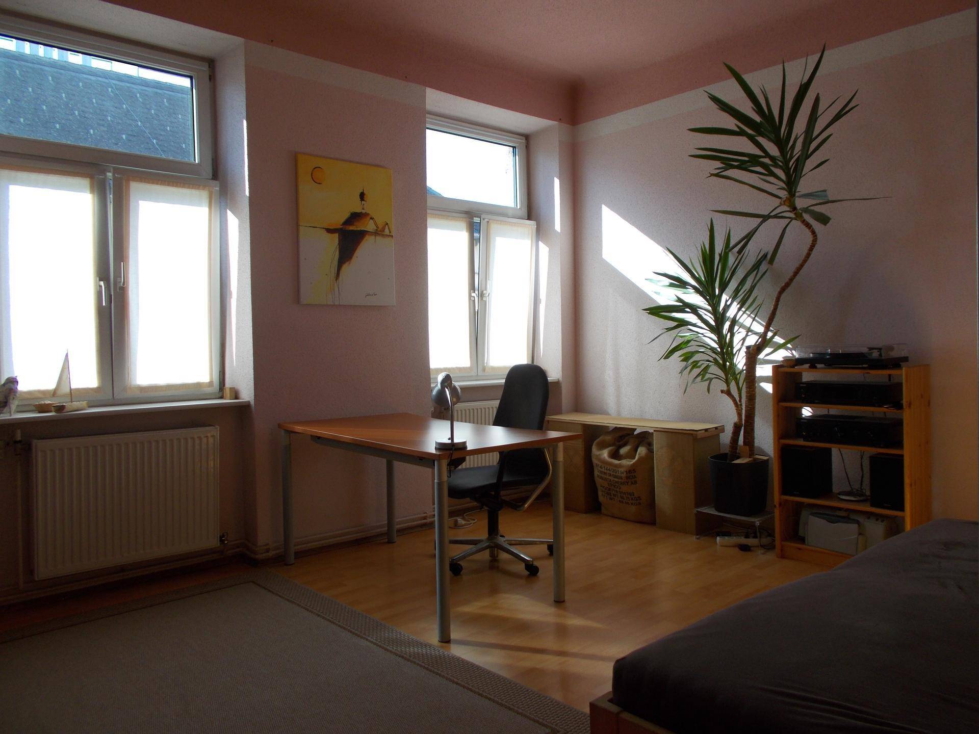 Heller Arbeitsbereich mit Schreibtisch, Pflanzen und Holzboden, ideal für Home-Office.