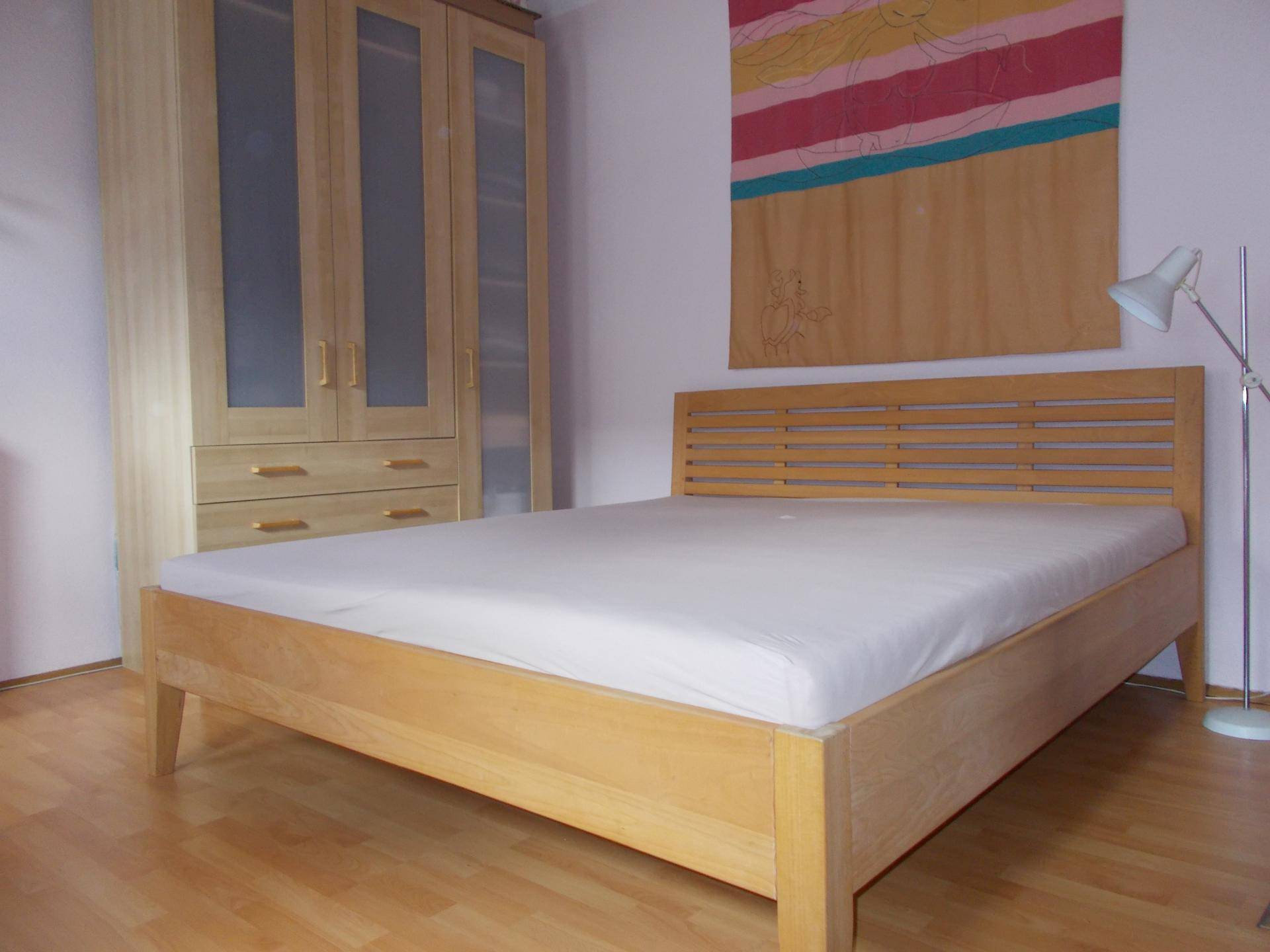 Schlafzimmer mit hellem Holzbett, passendem Kleiderschrank und Holzboden.