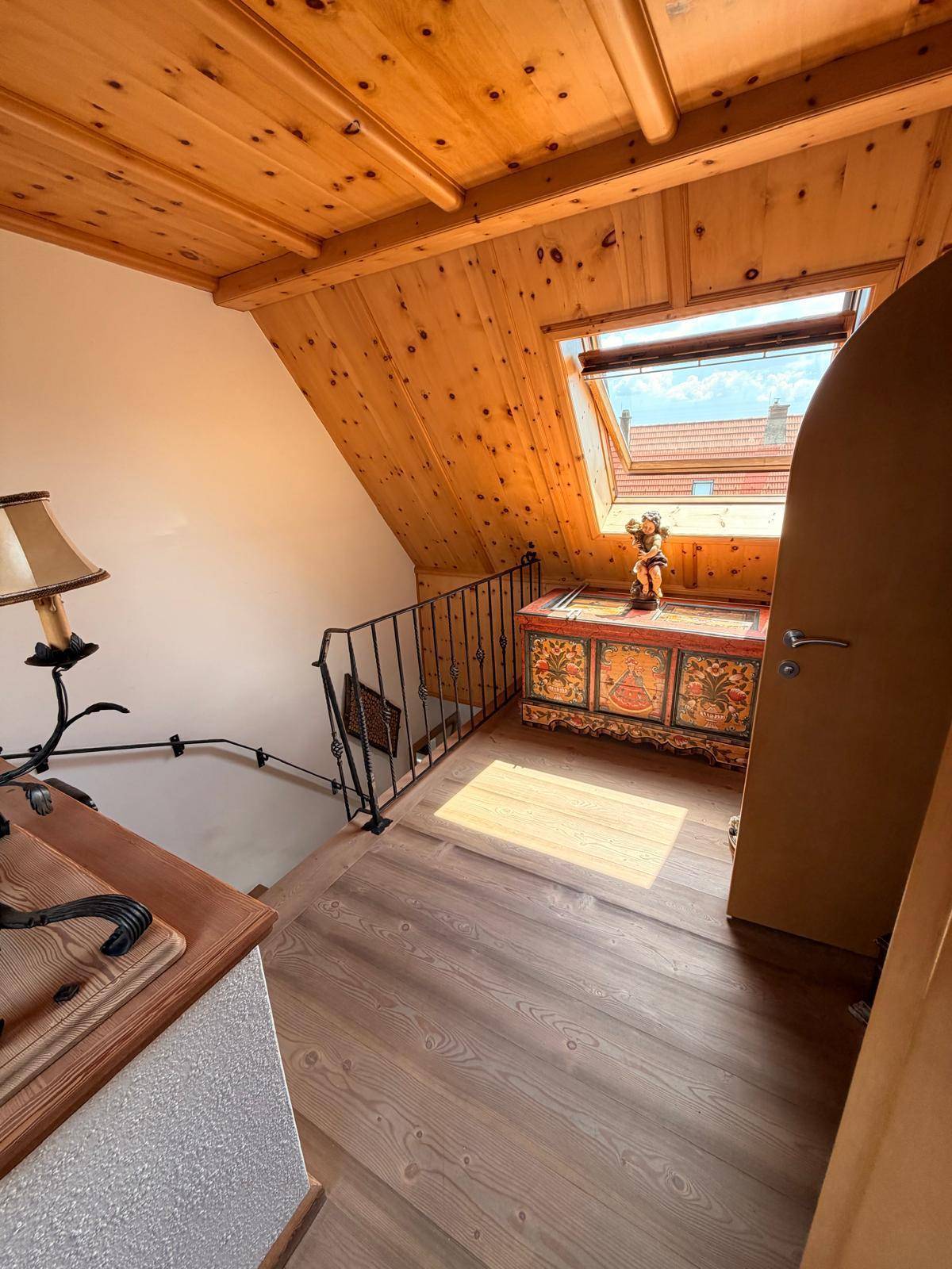Heller Flur im Dachgeschoss mit Holzboden, Dachfenster und traditioneller Truhe.