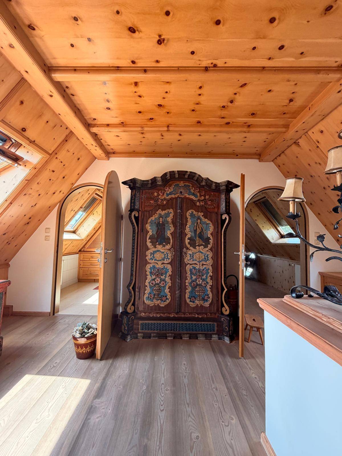 Heller Flur im Dachgeschoss mit Holzboden, Dachfenstern und traditionellem Bauernschrank.