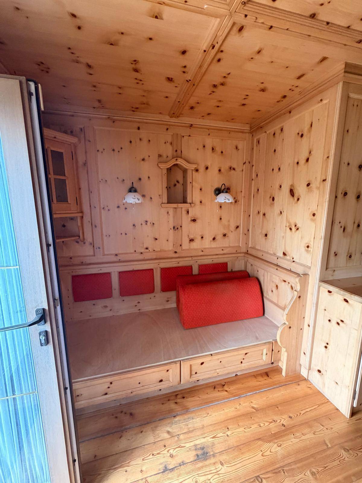 Gemütliches Zimmer mit holzvertäfelten Wänden, Decke und einer traditionellen Sitzecke.