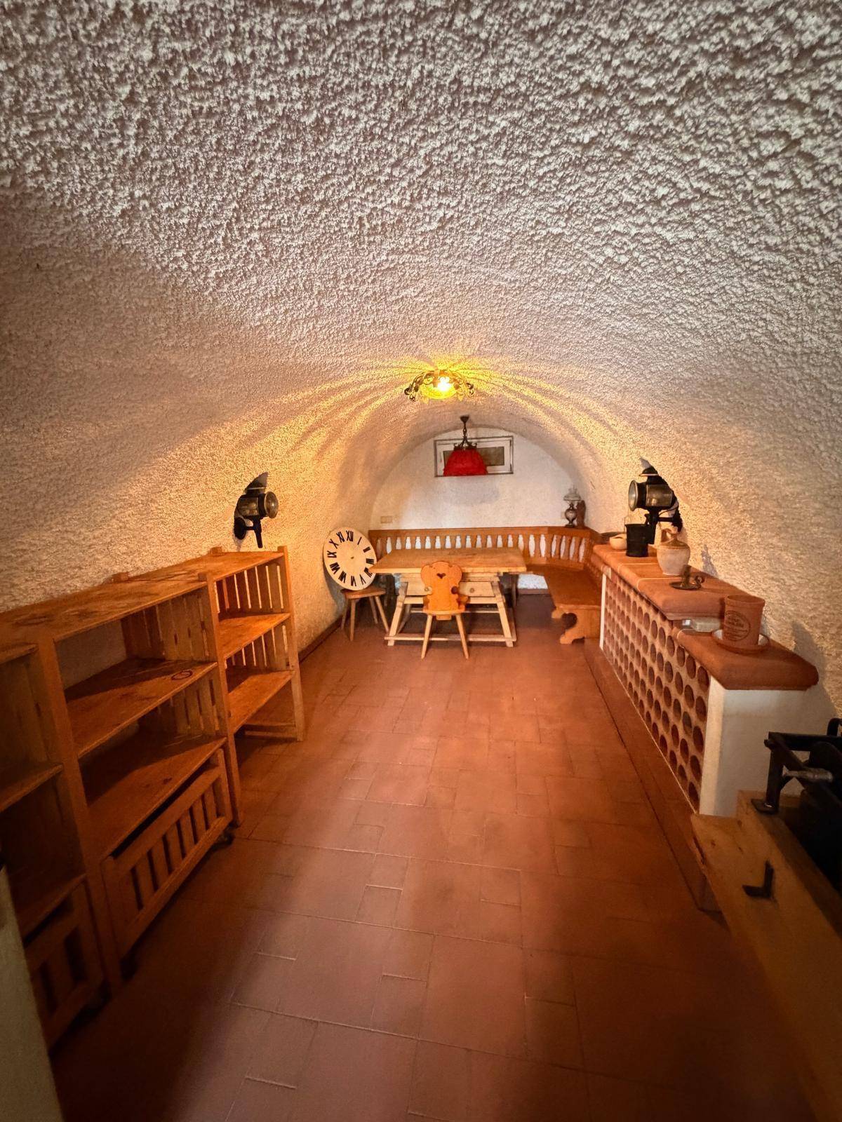Rustikaler Weinkeller mit Gewölbedecke, Terrakottafliesen und traditioneller Sitzecke.