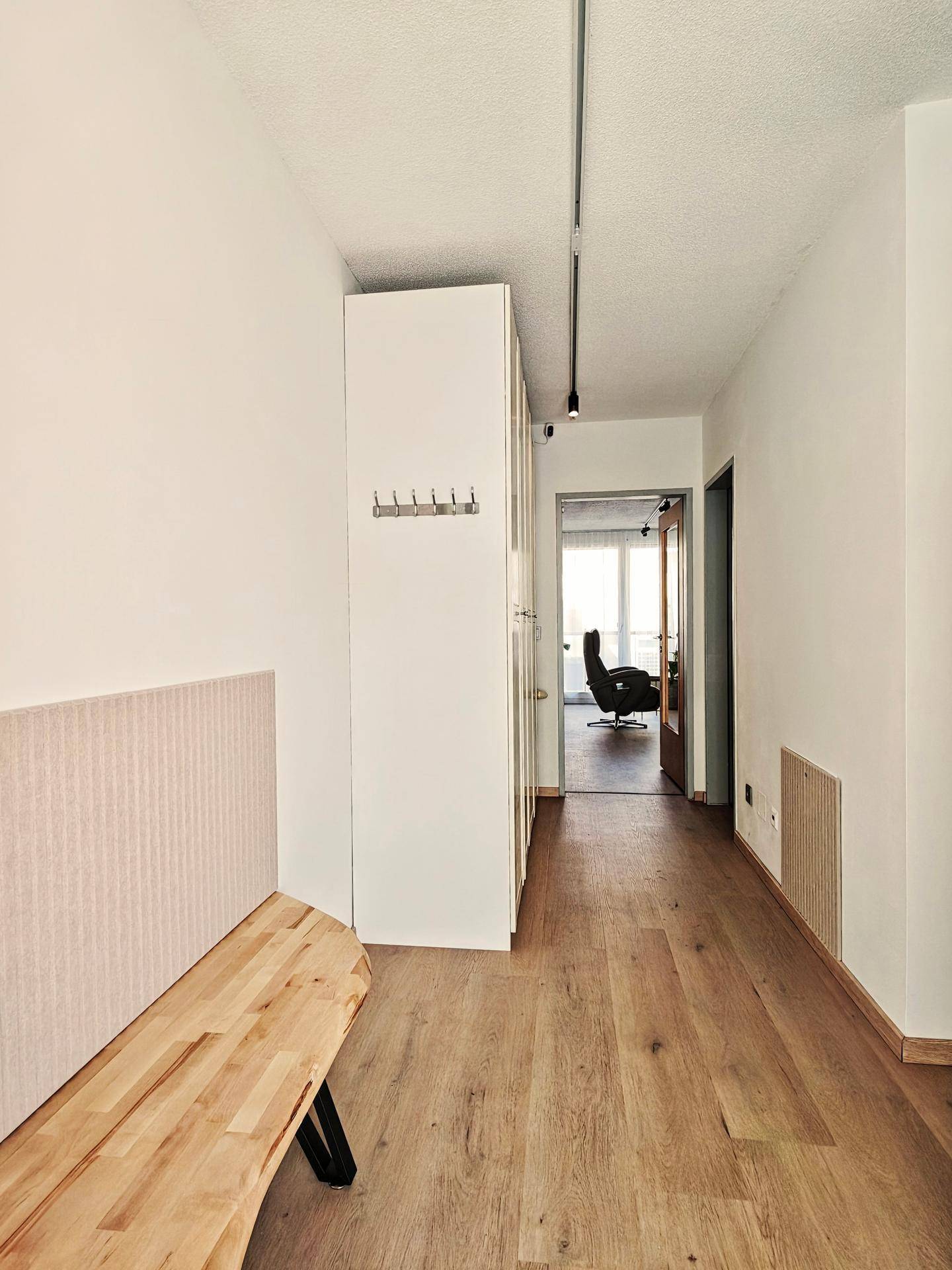 Heller Flur mit Holzboden, einer Sitzbank und Stauraum, der zu weiteren Räumen führt.