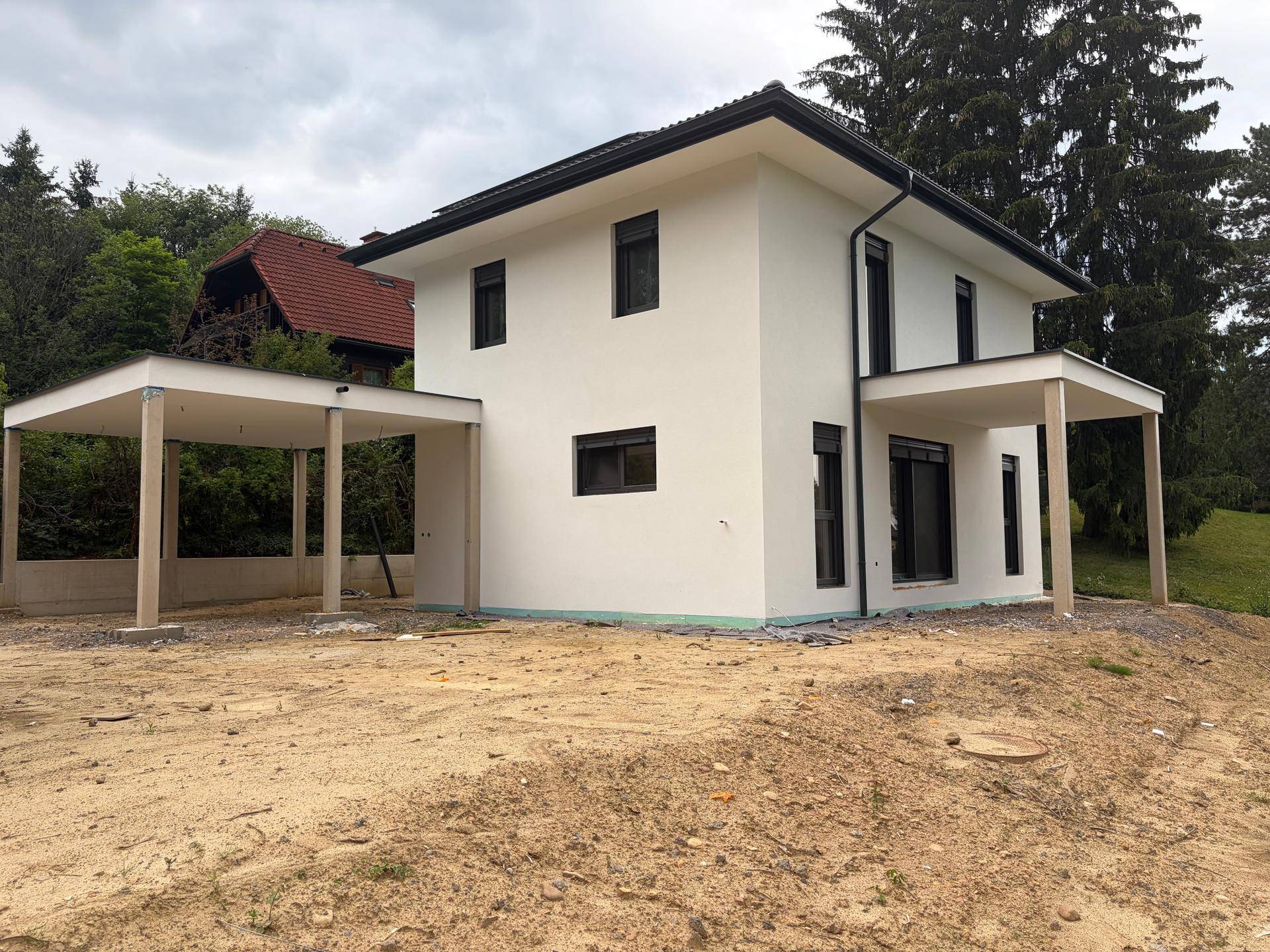 Neubau-Einfamilienhaus in der Bauphase mit Carport und unfertigem Gelände.