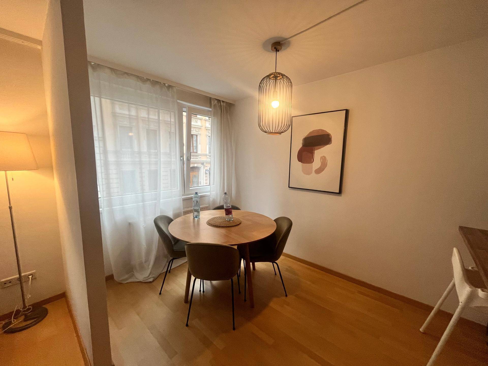 Heller Essbereich mit rundem Holztisch, modernen Stühlen und einem Fenster mit Tageslicht.