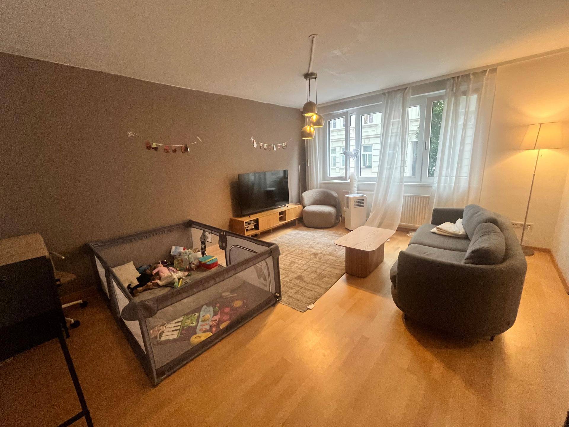 Helles Wohnzimmer mit Holzboden, bequemer Couch und einem Fenster mit Blick nach draußen.