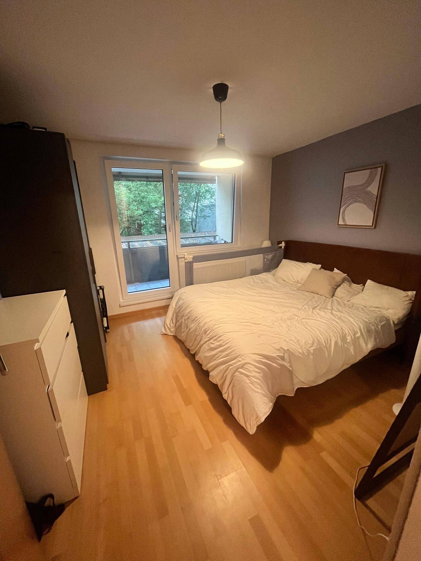 Schlafzimmer mit Holzboden, Doppelbett und direktem Zugang zu einem Balkon.