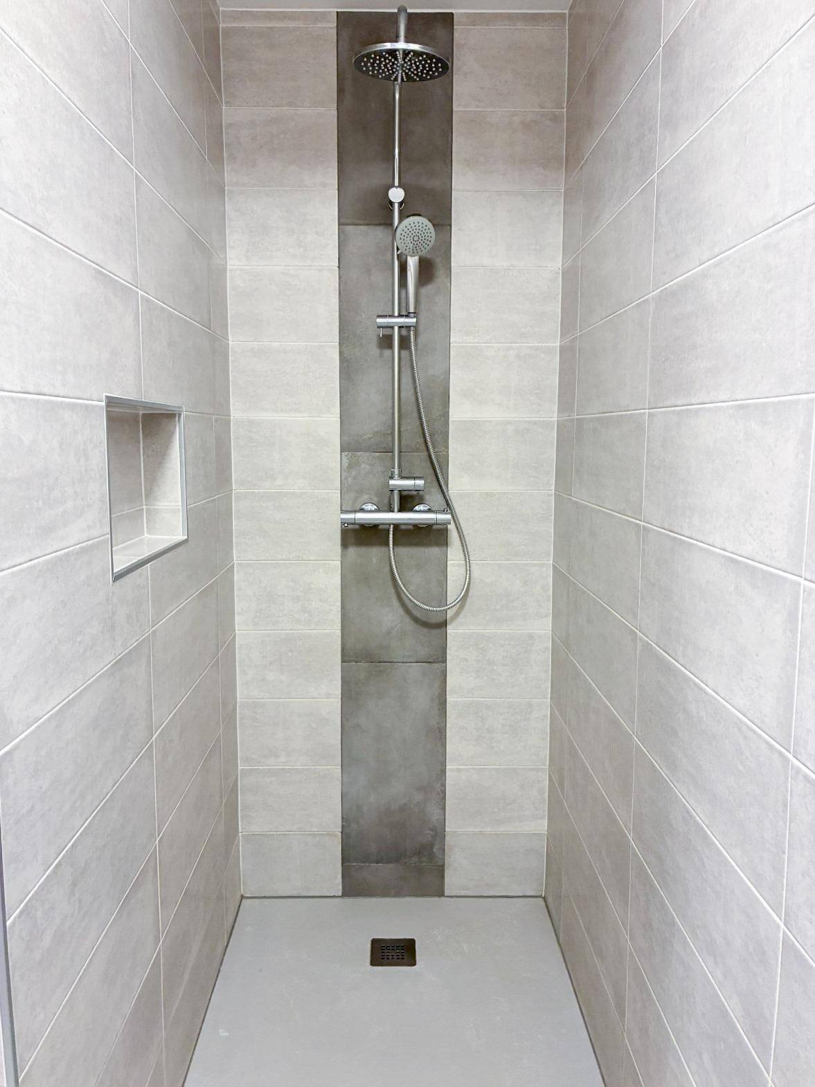 Moderne begehbare Dusche mit Regenduschkopf und hellen Fliesen.