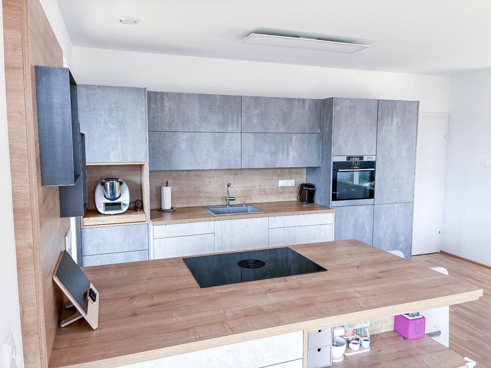Moderne Einbauküche mit grauen Fronten, Holzarbeitsplatte und integriertem Backofen.