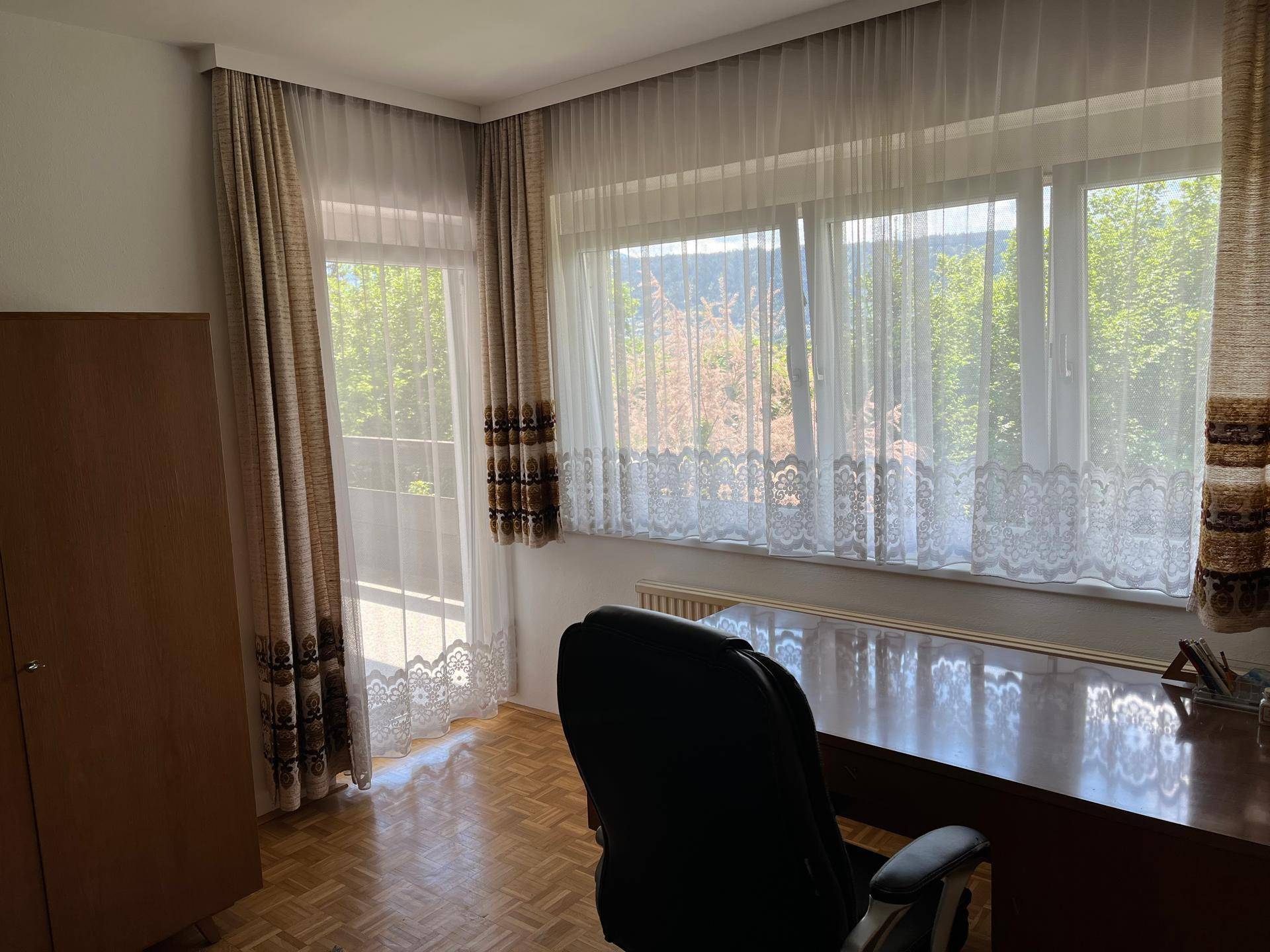 Lichtdurchflutetes Schlafzimmer mit Zugang zum Balkon und weitem Blick auf die umliegende Natur.