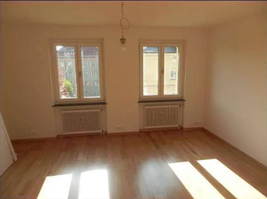 Helles Zimmer mit Holzboden, zwei Fenstern und viel natürlichem Lichteinfall.