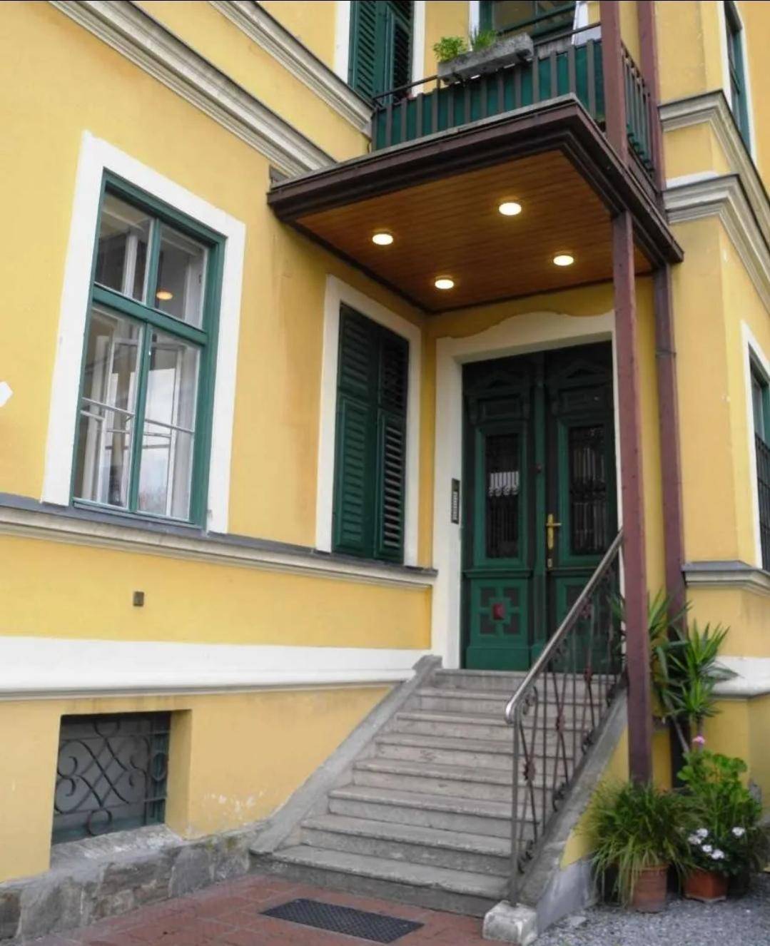 Repräsentativer Eingangsbereich eines historischen Gebäudes mit grünen Türen und Fensterläden.
