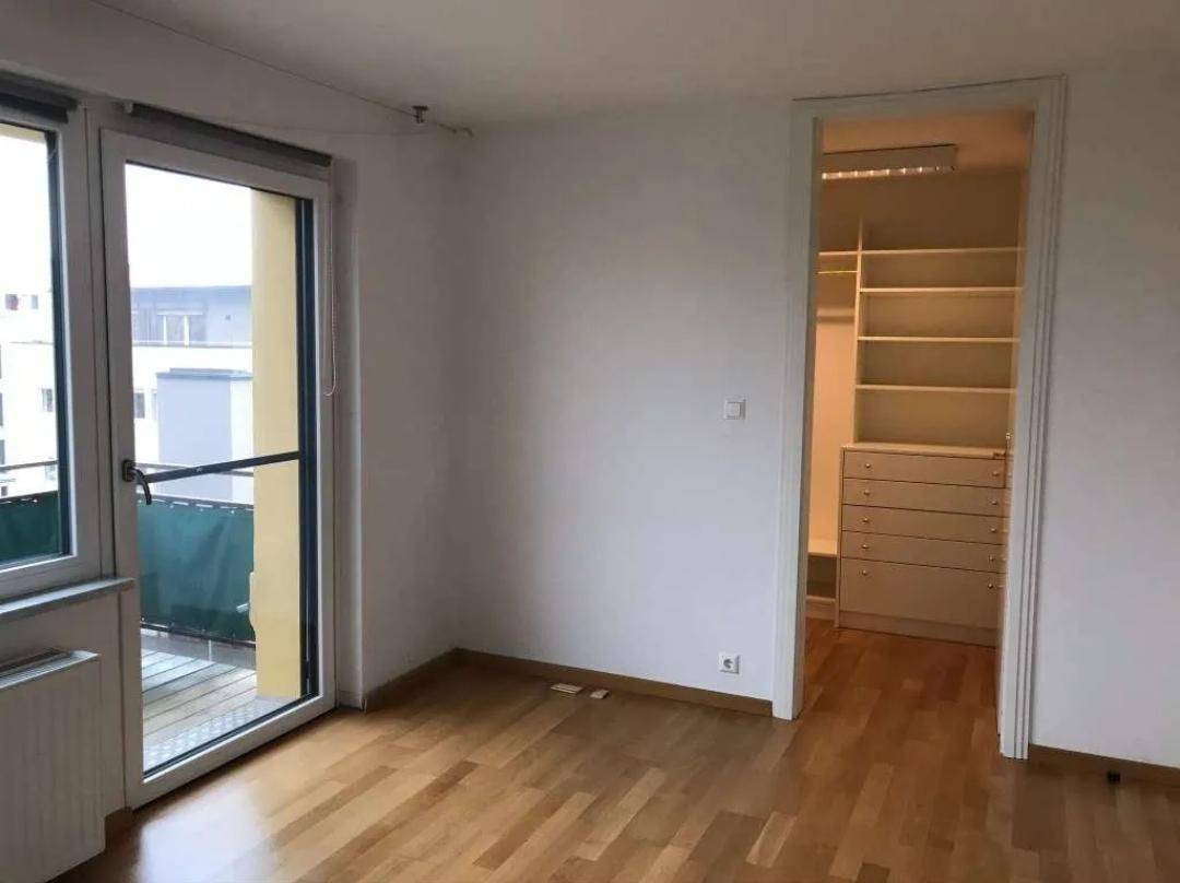 Helles Zimmer mit Holzboden, Balkonzugang und einem begehbaren Kleiderschrank.