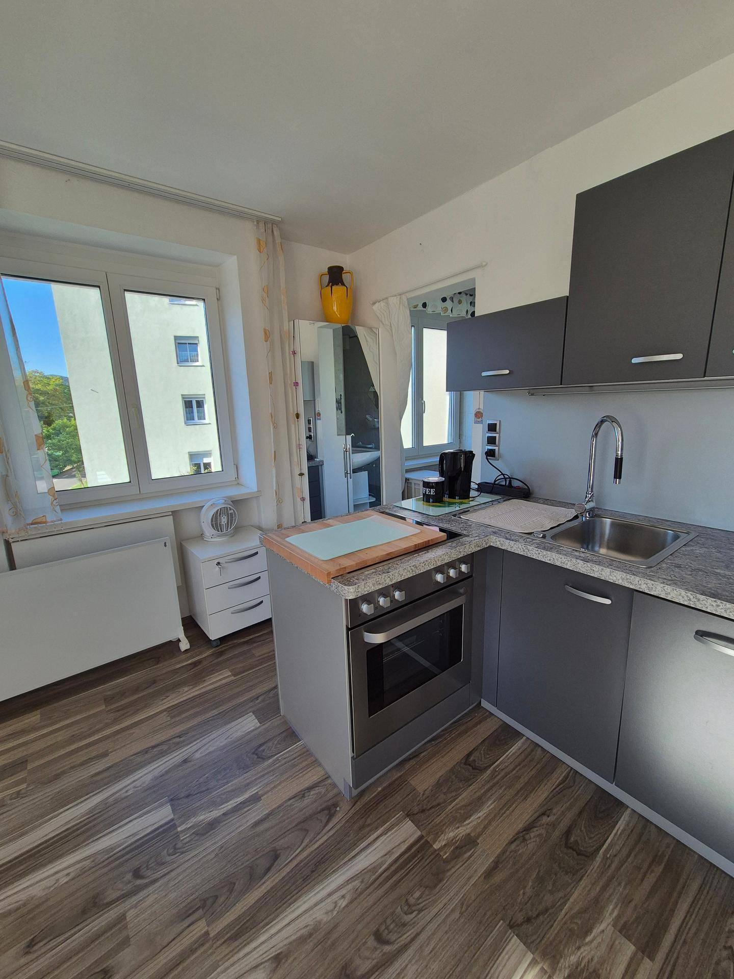 Funktionale Küchenzeile mit grauen Schränken, integriertem Herd und Fenster.