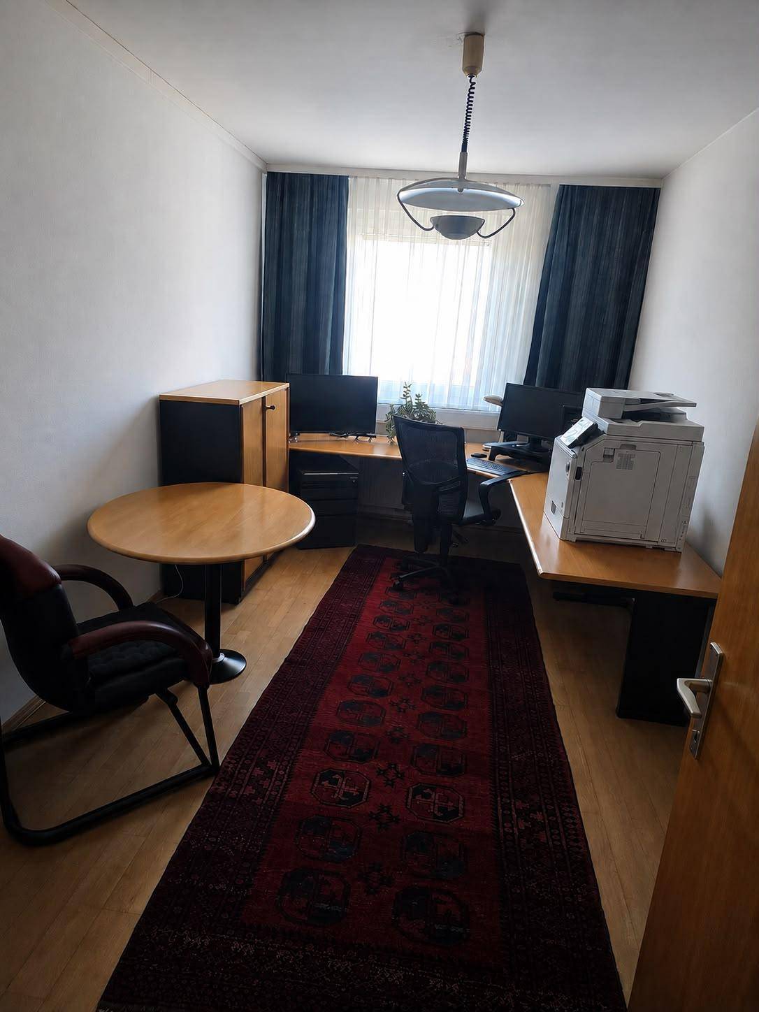 Funktionales Heimbüro mit zwei Arbeitsplätzen, Parkettboden und einem langen Teppich.