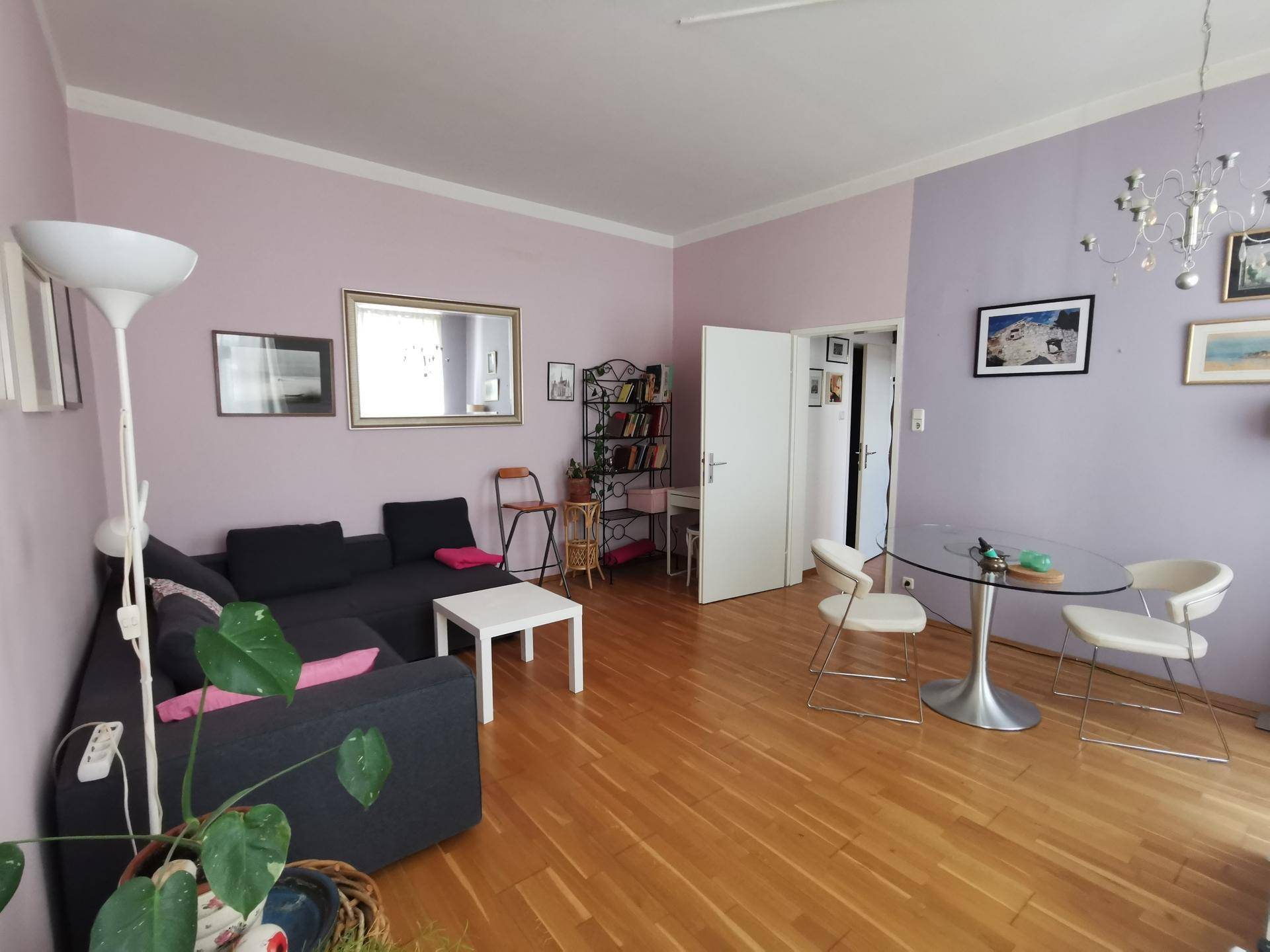 Heller Wohnbereich mit Parkettboden, farbigen Wänden und einem modernen Sofa.