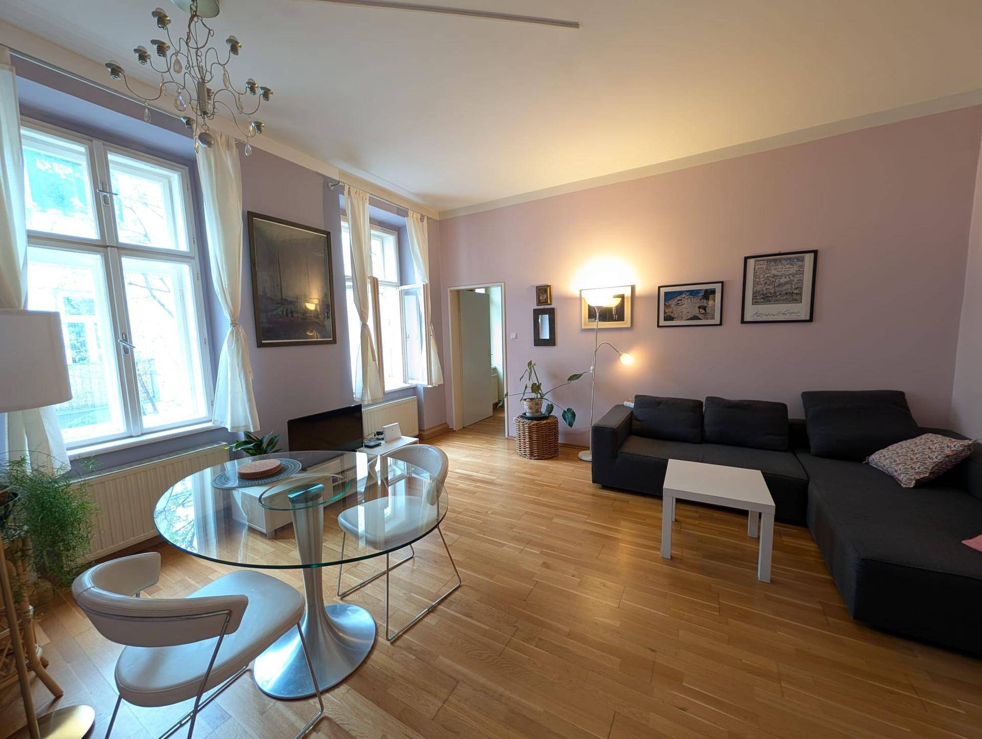 Geräumiges Wohn-Esszimmer mit Holzboden, lavendelfarbenen Wänden und bequemer Sitzecke.