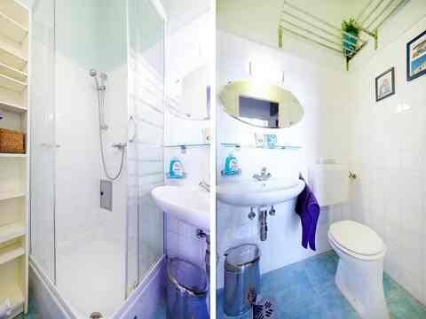Kompaktes Badezimmer mit Duschkabine, Waschbecken und WC, ausgestattet mit blauen Fliesen.
