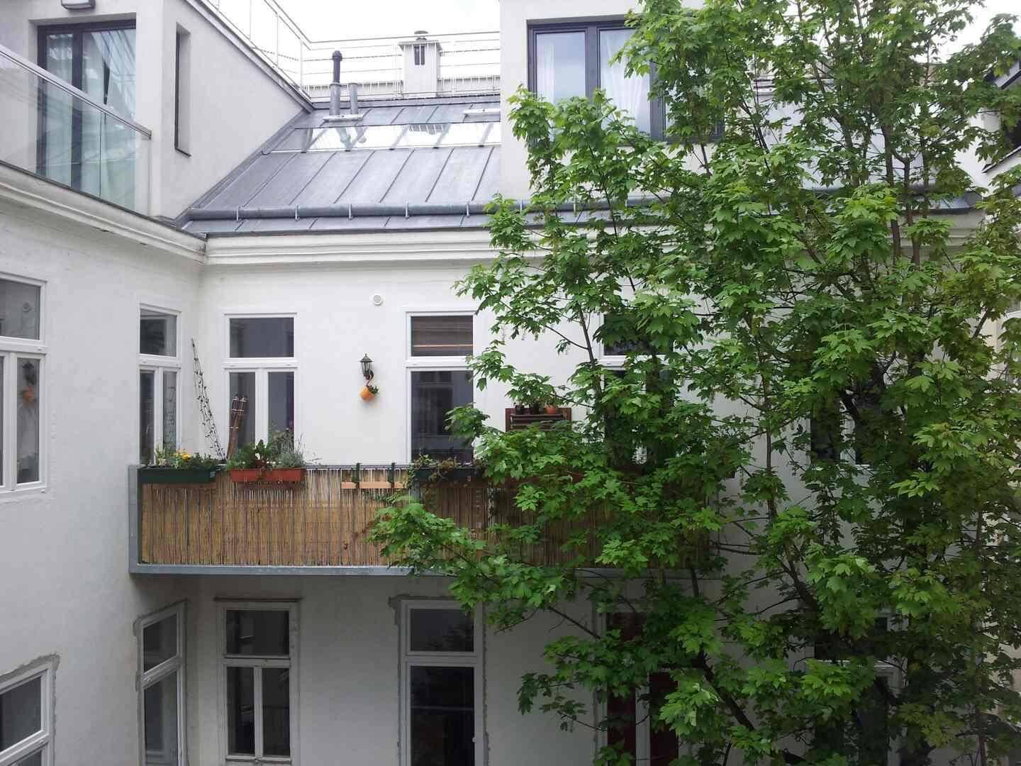 Ruhiger Innenhof mit einem Balkon und üppigem Grün, das eine entspannte Atmosphäre schafft.