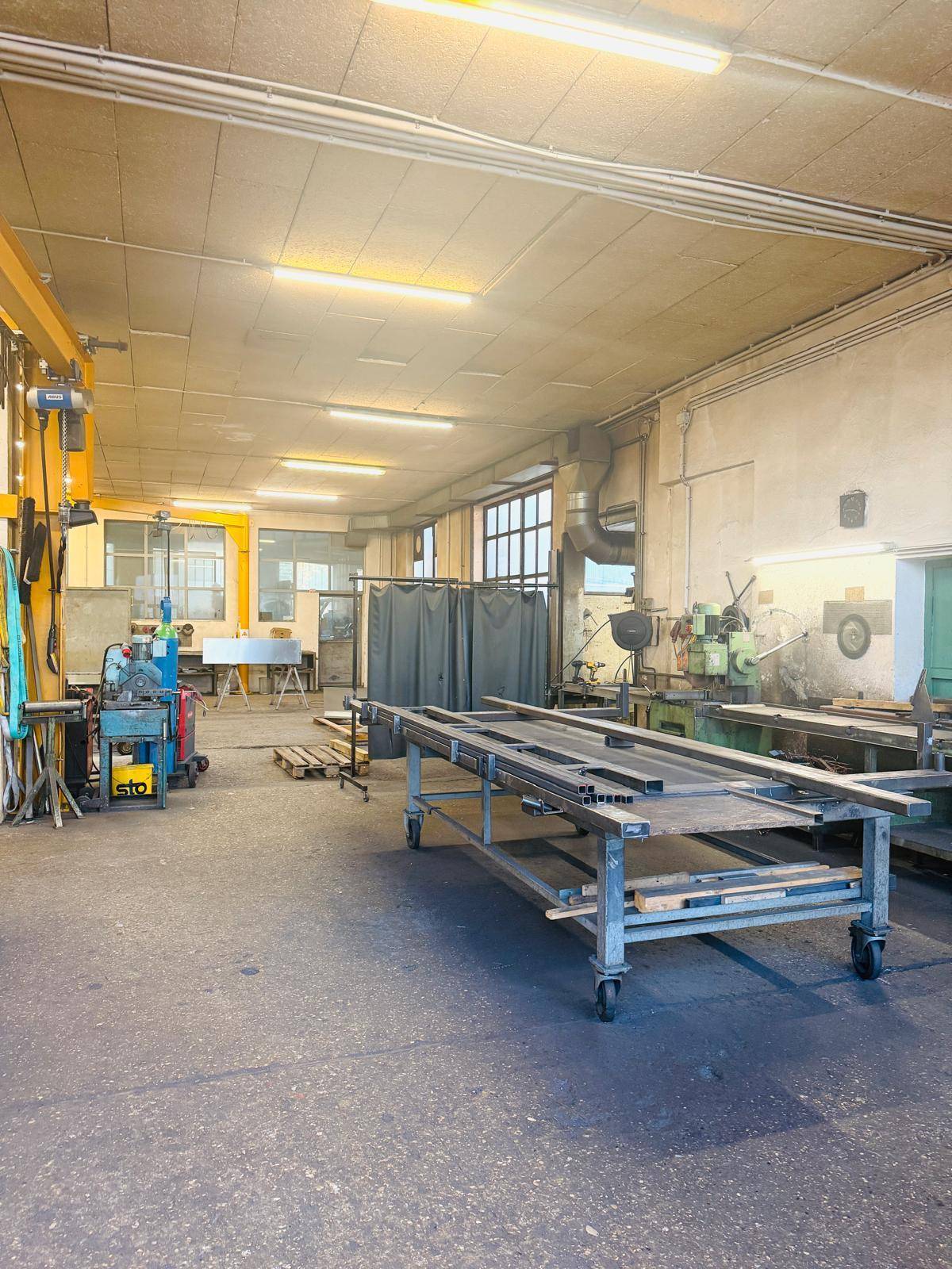 Geräumige Werkstatt mit Maschinen, Werkbänken und industrieller Beleuchtung, bereit für die Produktion.
