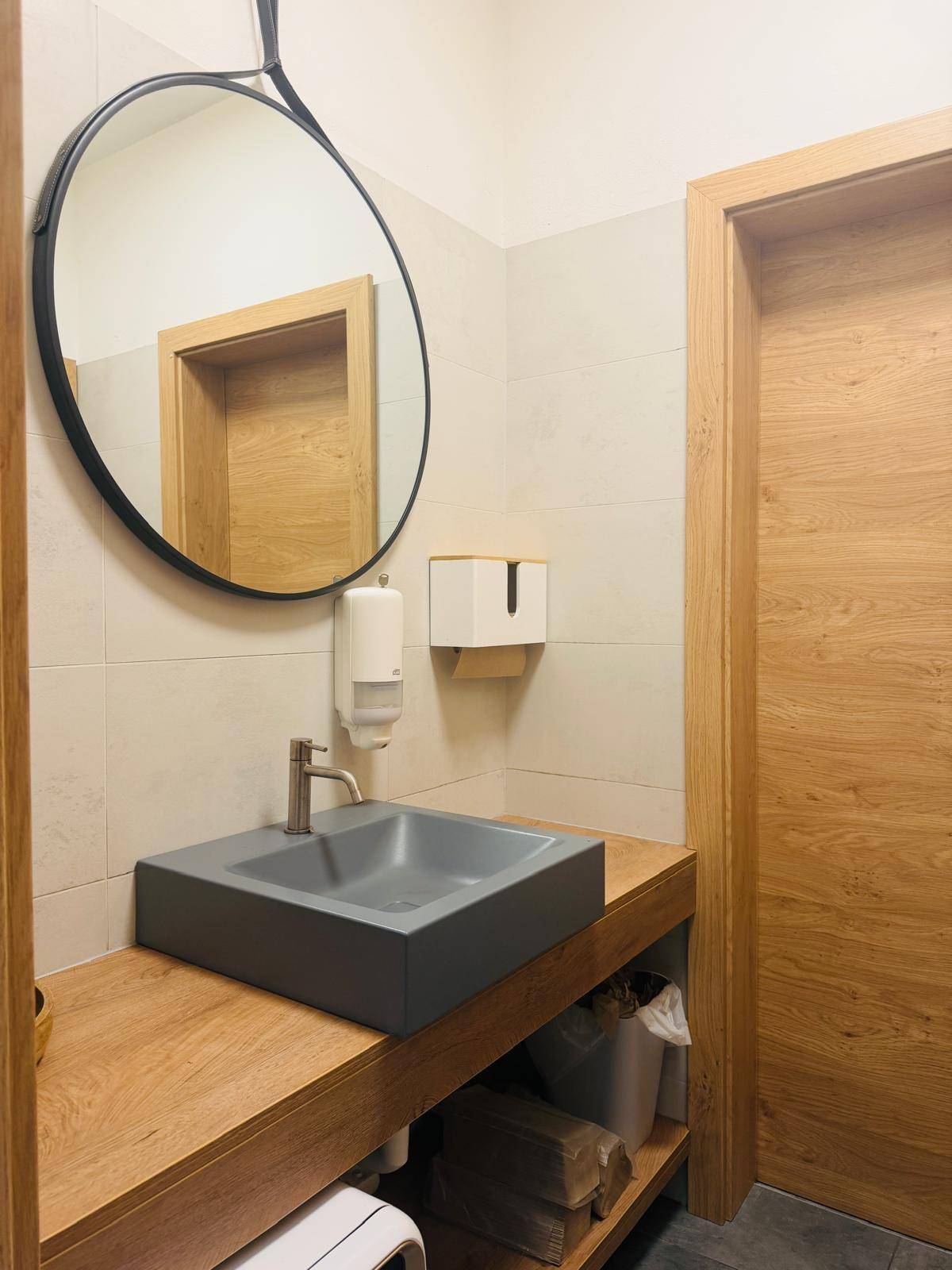 Modernes WC mit Aufsatzwaschbecken, großem Spiegel und Holzelementen, sauber und gut gepflegt.